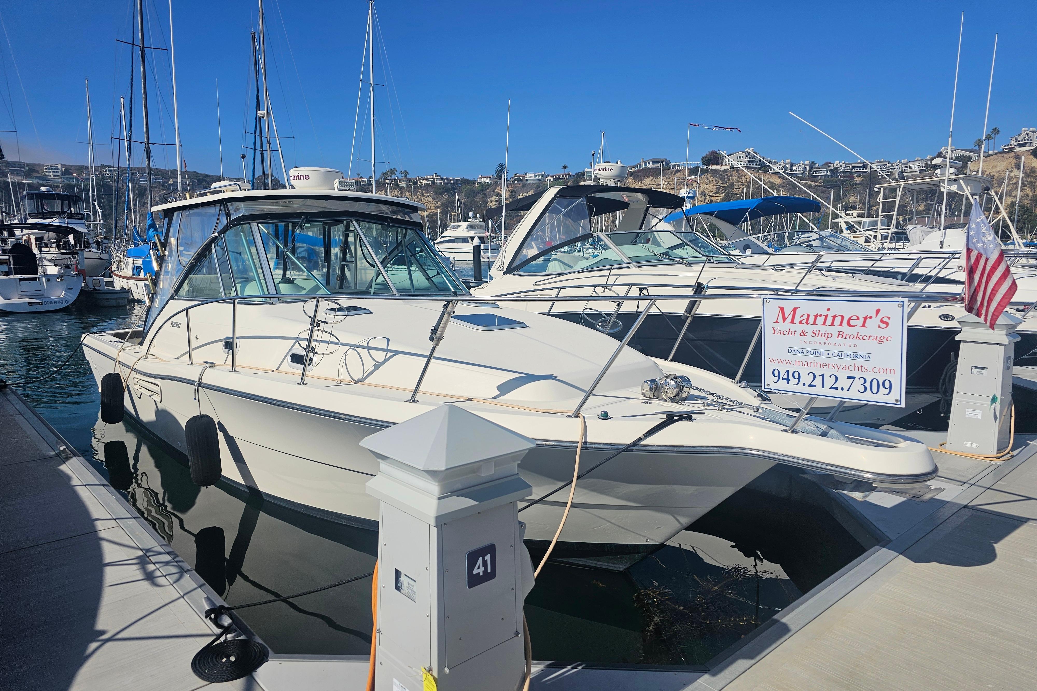 2001 Pursuit 3000 Express boat docked at marina with brokerage sign.