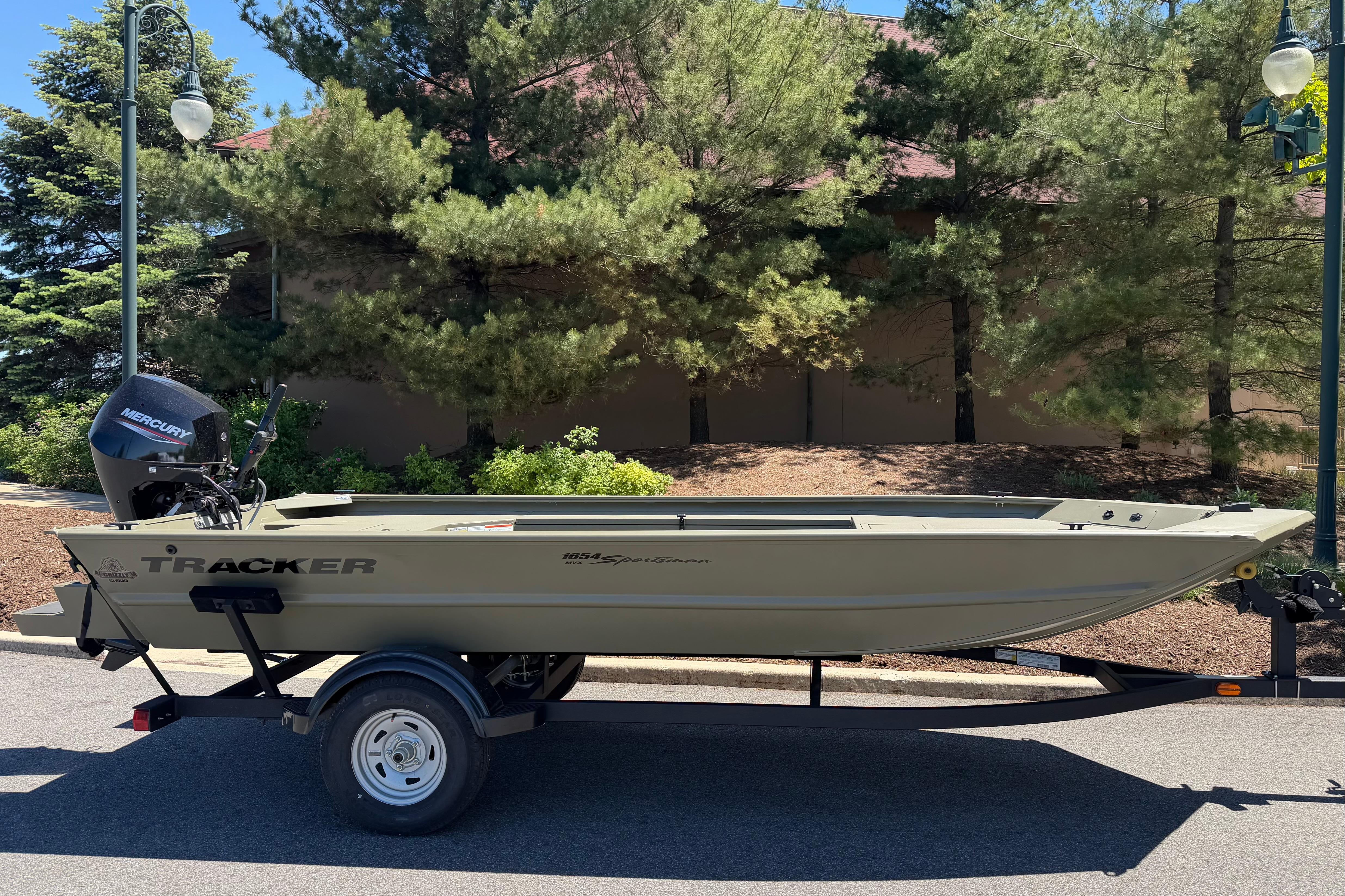 2026 Tracker Grizzly 1654 T Sportsman boat on trailer, parked outdoors.