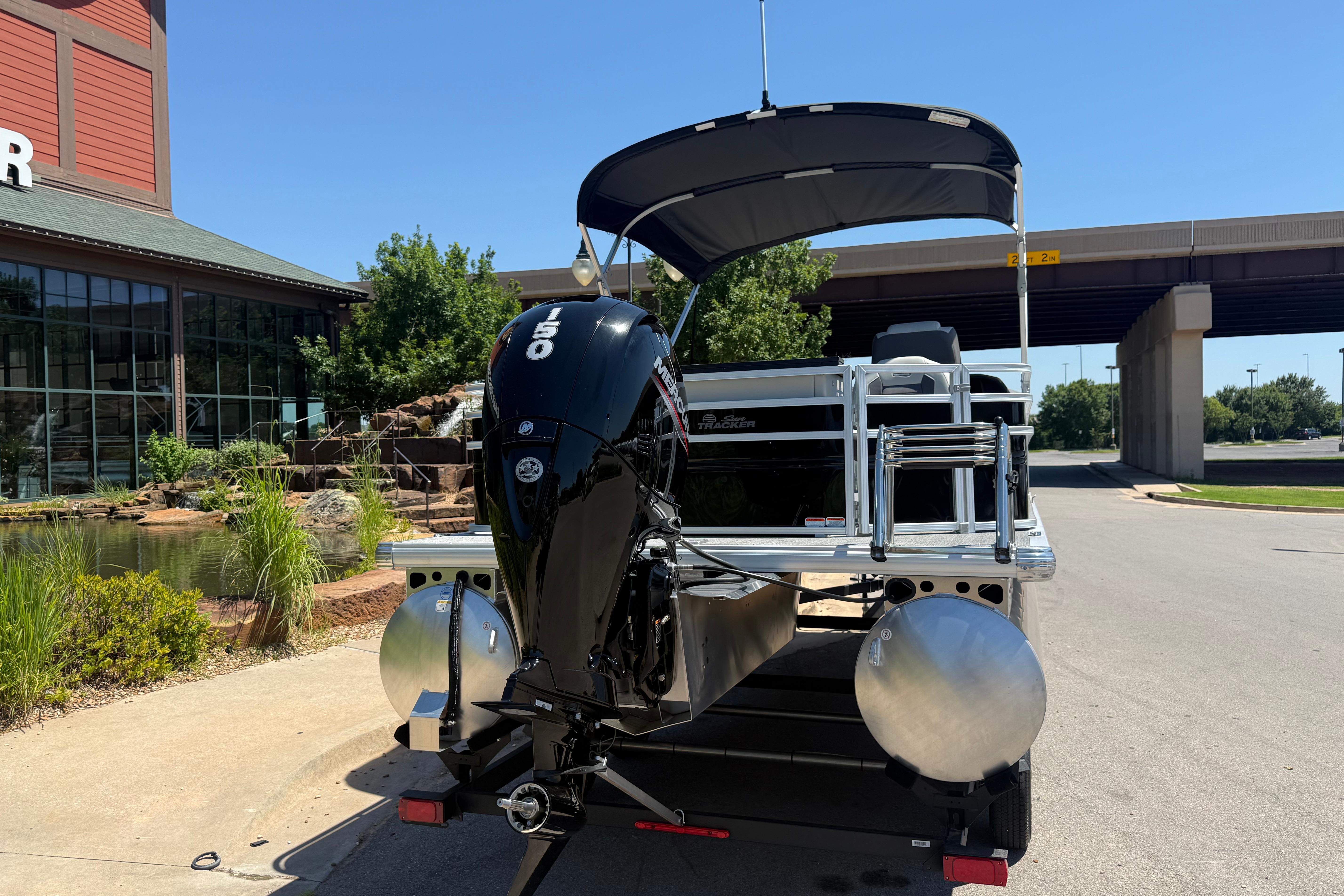 2026 Sun Tracker Fishin' Barge 22 DLX with 150 HP engine, parked outdoors.