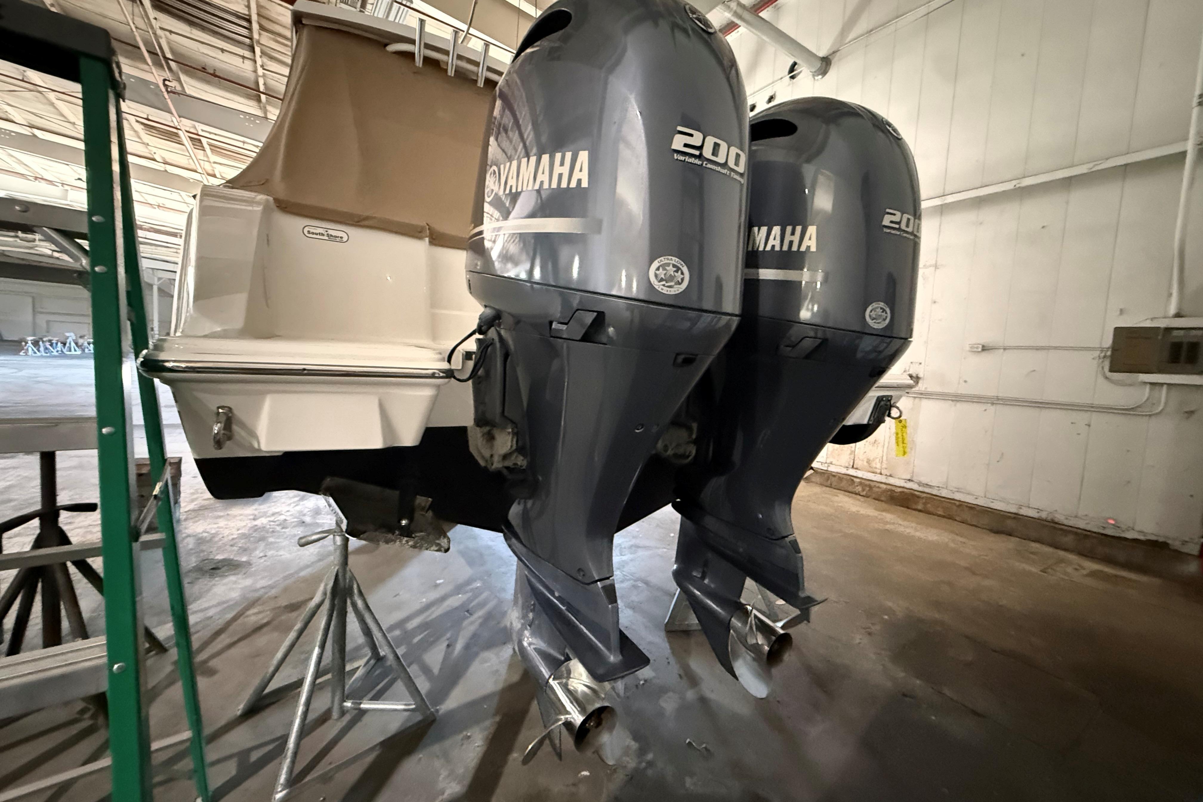 2021 Pursuit S 268 Sport boat with dual Yamaha 200 outboard engines in a warehouse.
