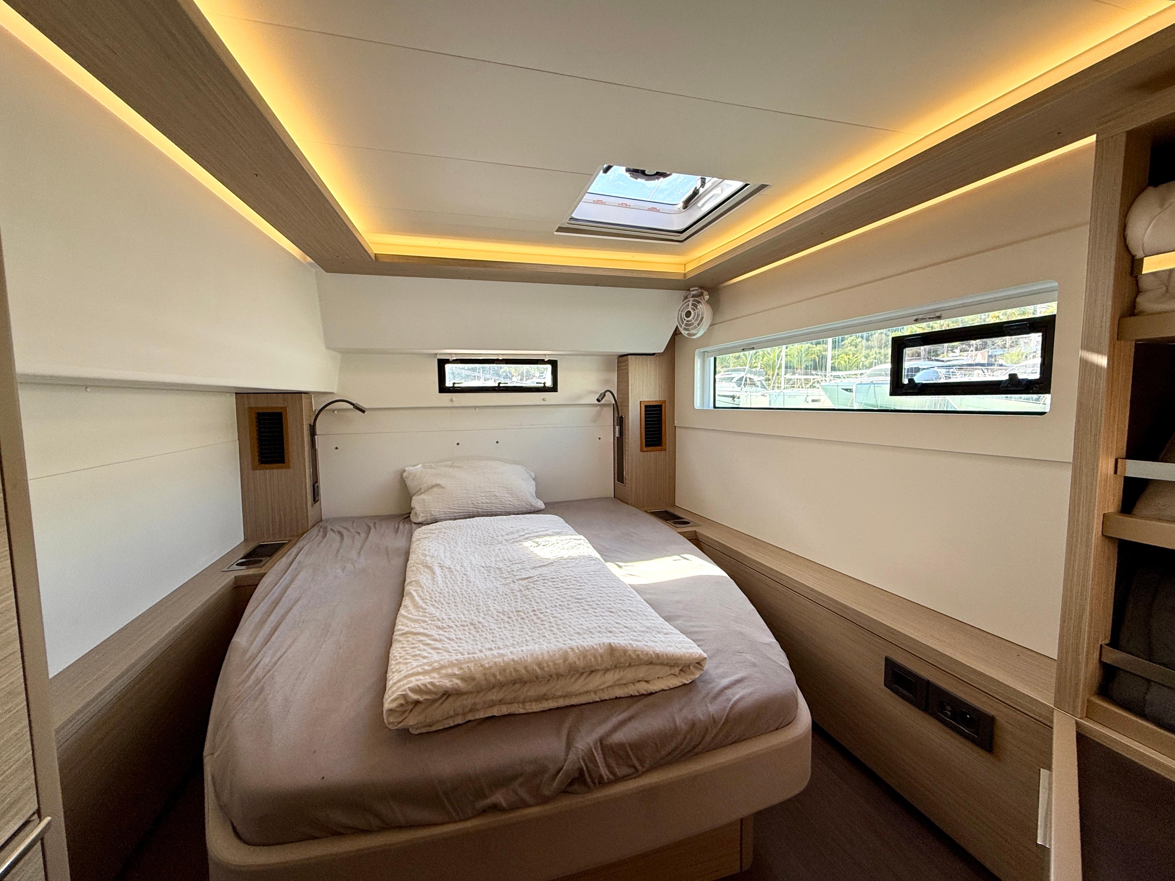 Luxurious bedroom interior of 2023 Lagoon 46 yacht with modern lighting and cozy bedding.