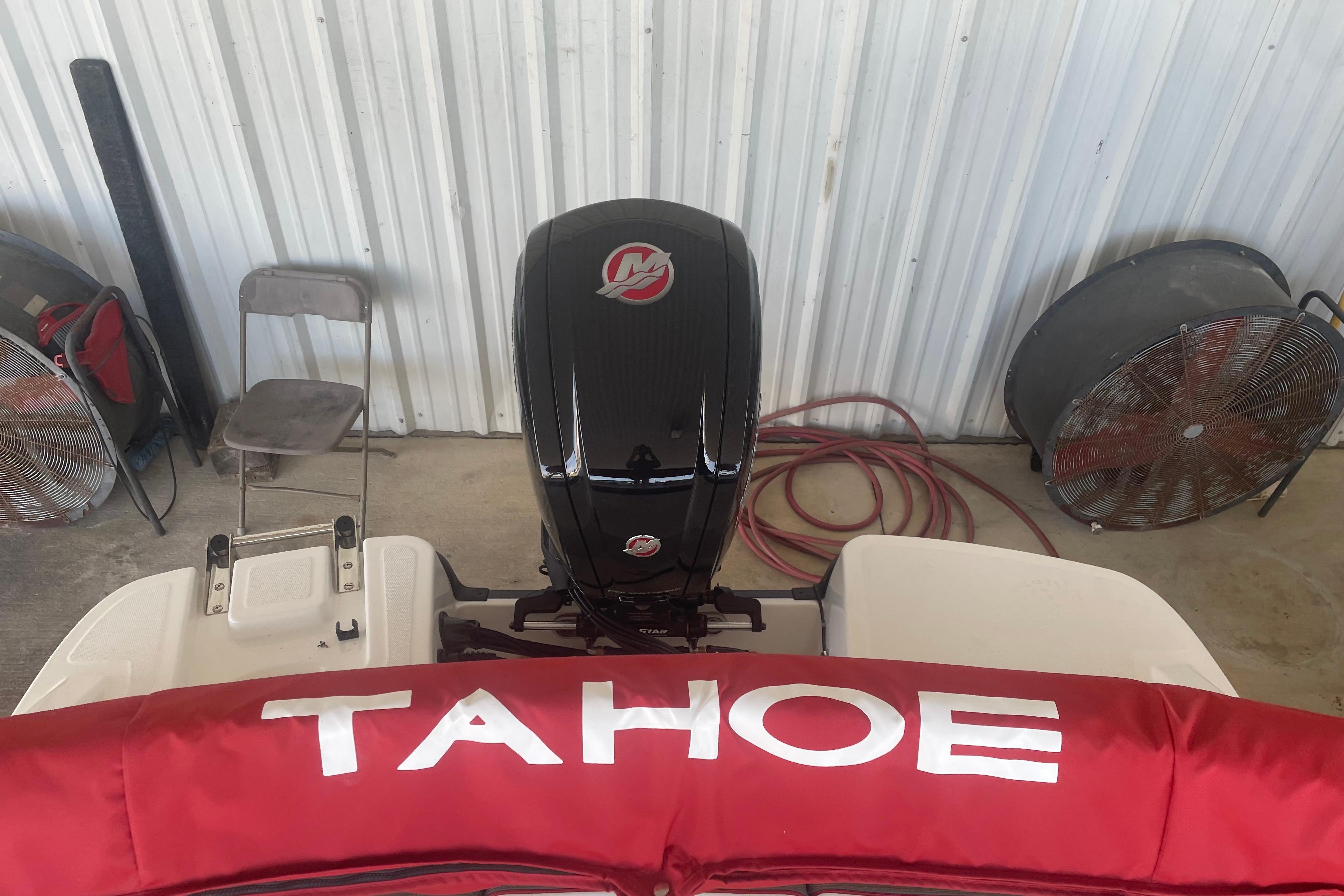 2026 Tahoe T18 boat with red cover and outboard motor in a garage.