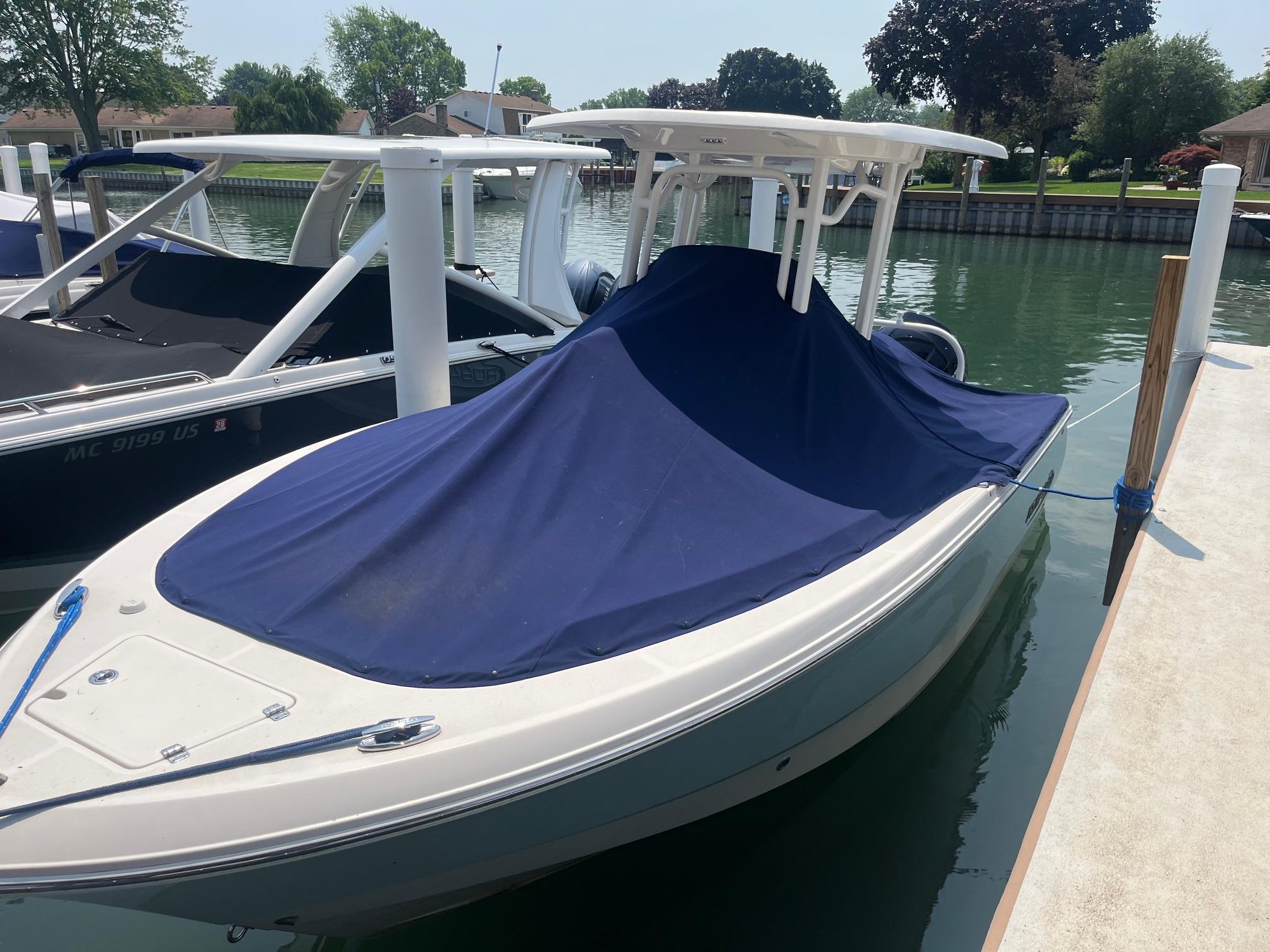 2020 Robalo R230 Center Console boat docked with blue cover.