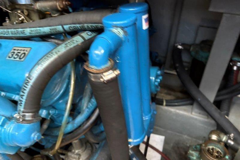 Engine compartment of 1987 Tollycraft 34 Sundeck Motor Yacht, featuring blue hoses and components.