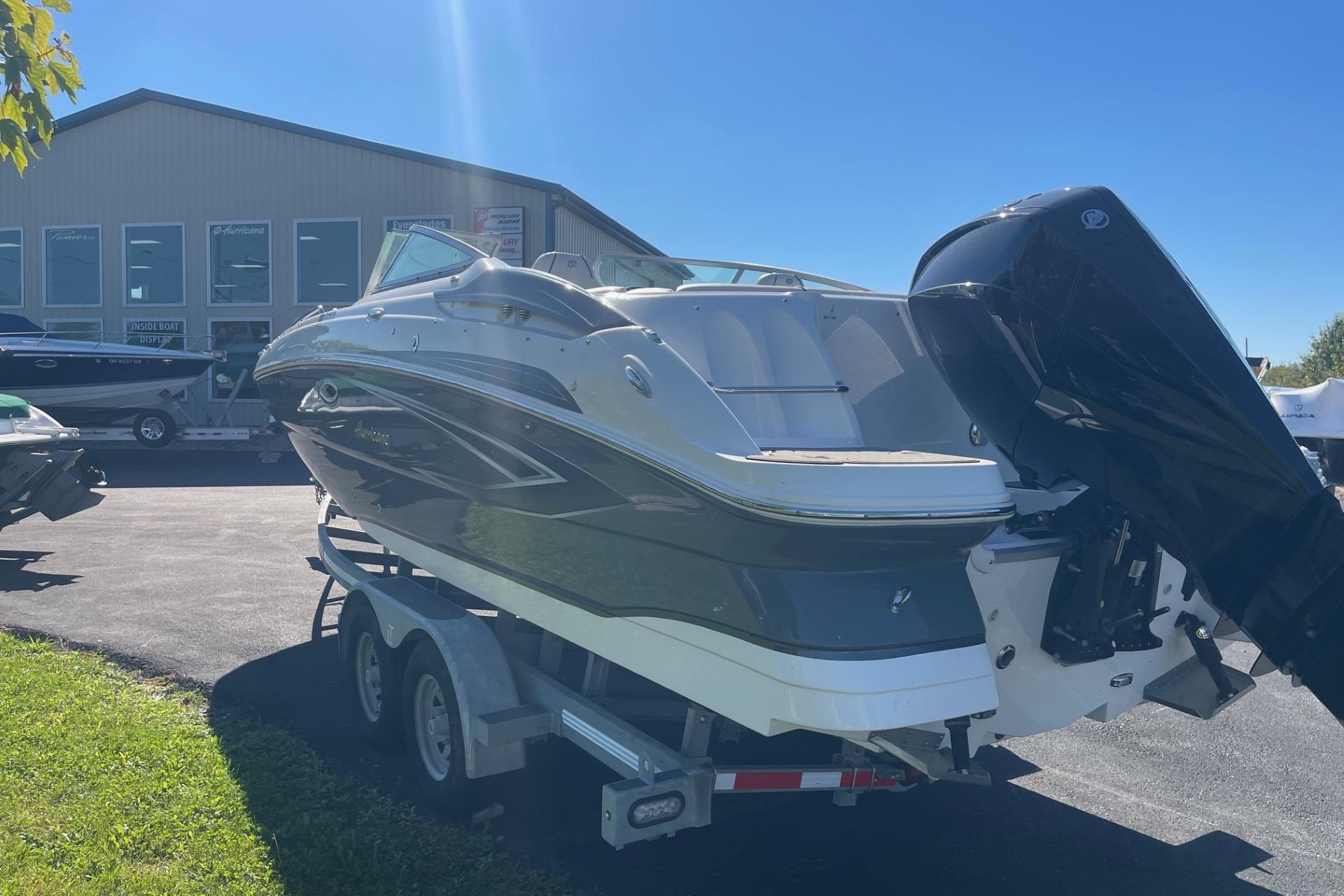 2023 Hurricane SunDeck 2400 OB boat on trailer, parked outside dealership.