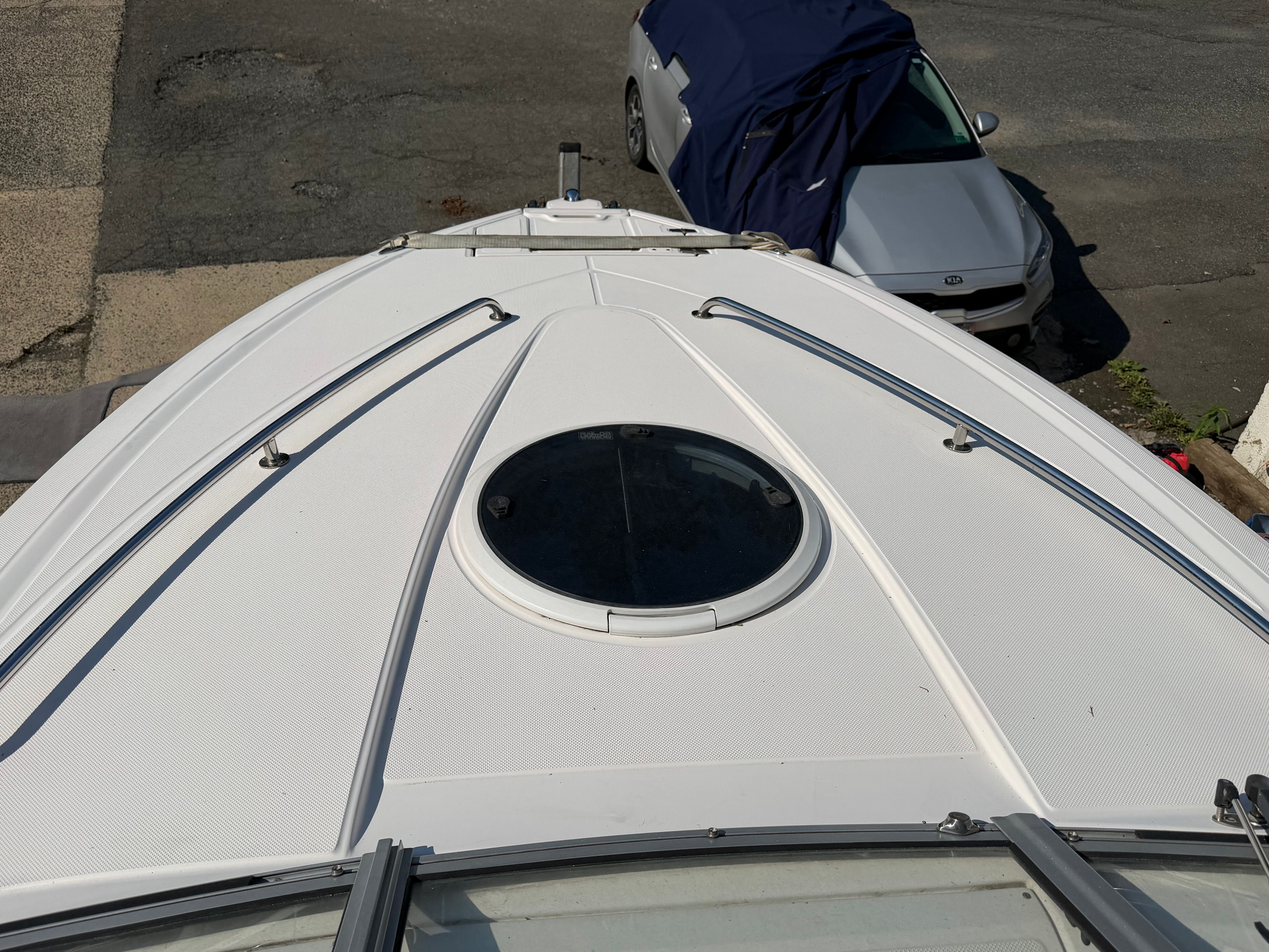 The image shows the foredeck of a 2011 Regal 2750 Cuddy boat with a round hatch.