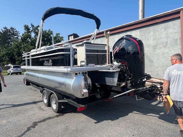2026 Sun Tracker Fishin' Barge 20 DLX on trailer, parked outdoors.