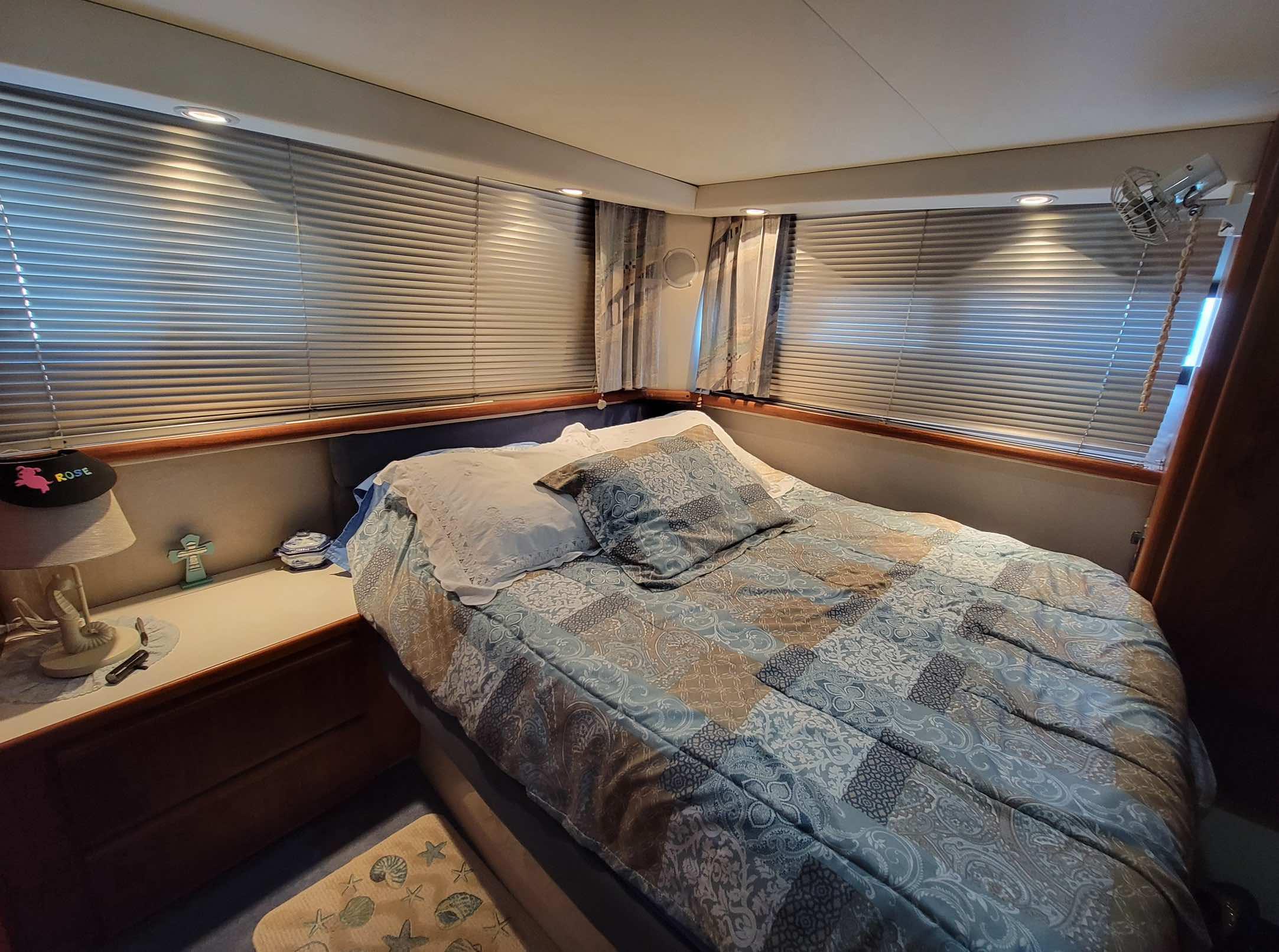 Cozy bedroom in 1992 Carver 33 Aft Cabin yacht with patterned bedding and window blinds.