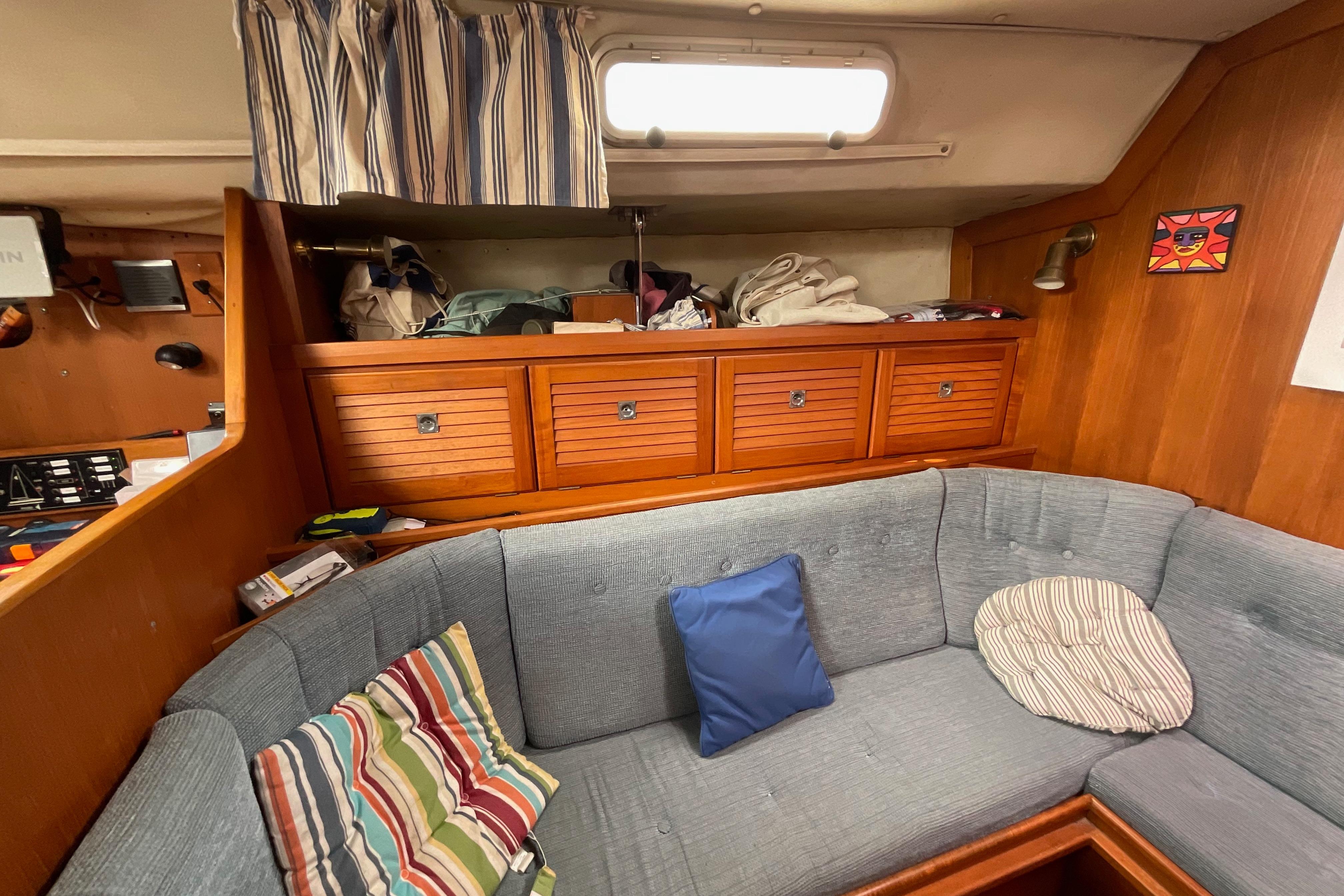 Cozy interior of 1988 Westerly Corsair 36 sailboat with striped cushions and wooden cabinetry.
