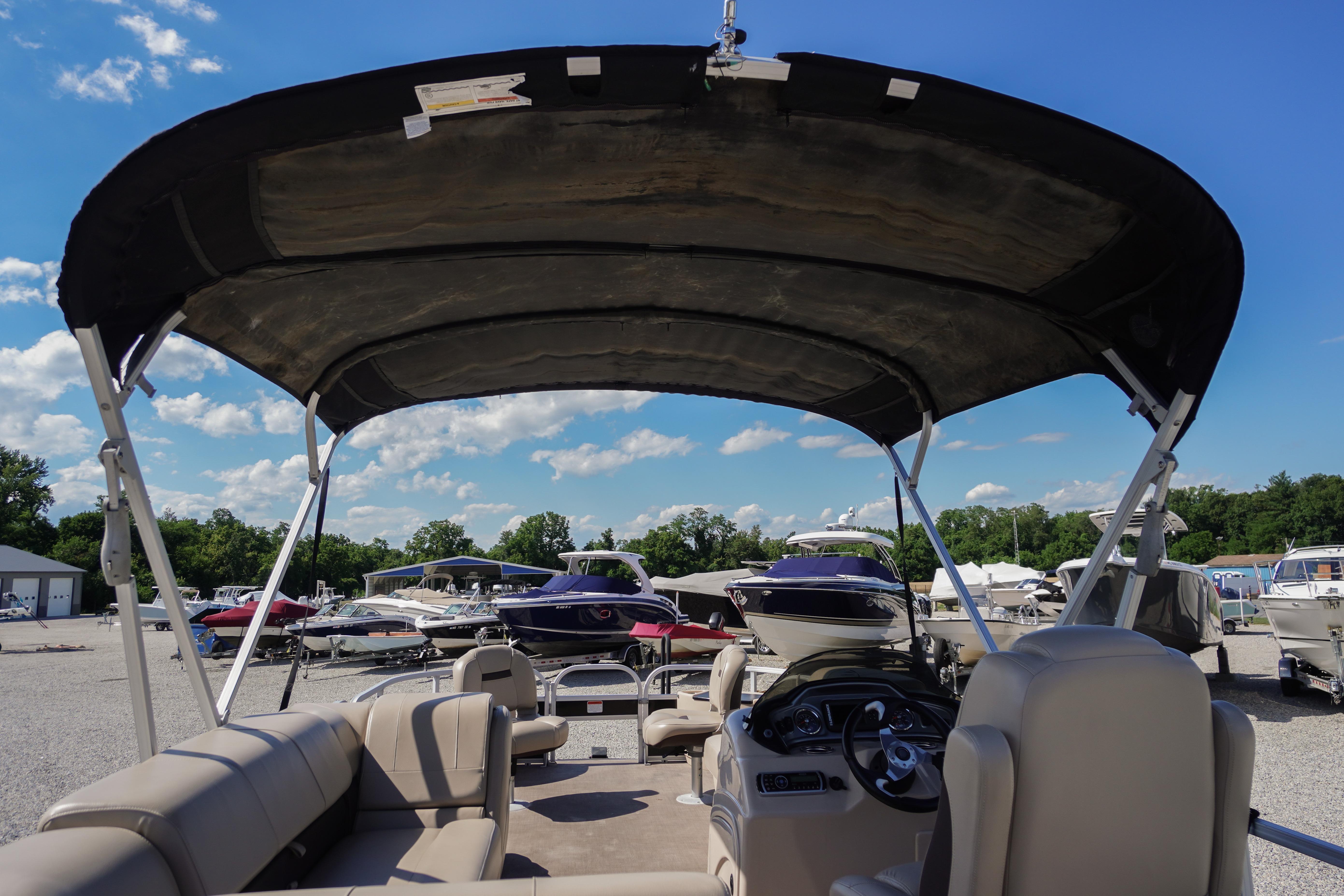 2019 SUNTRACKER Fishin' Barge 22 DLX pontoon boat with canopy, parked in a marina.