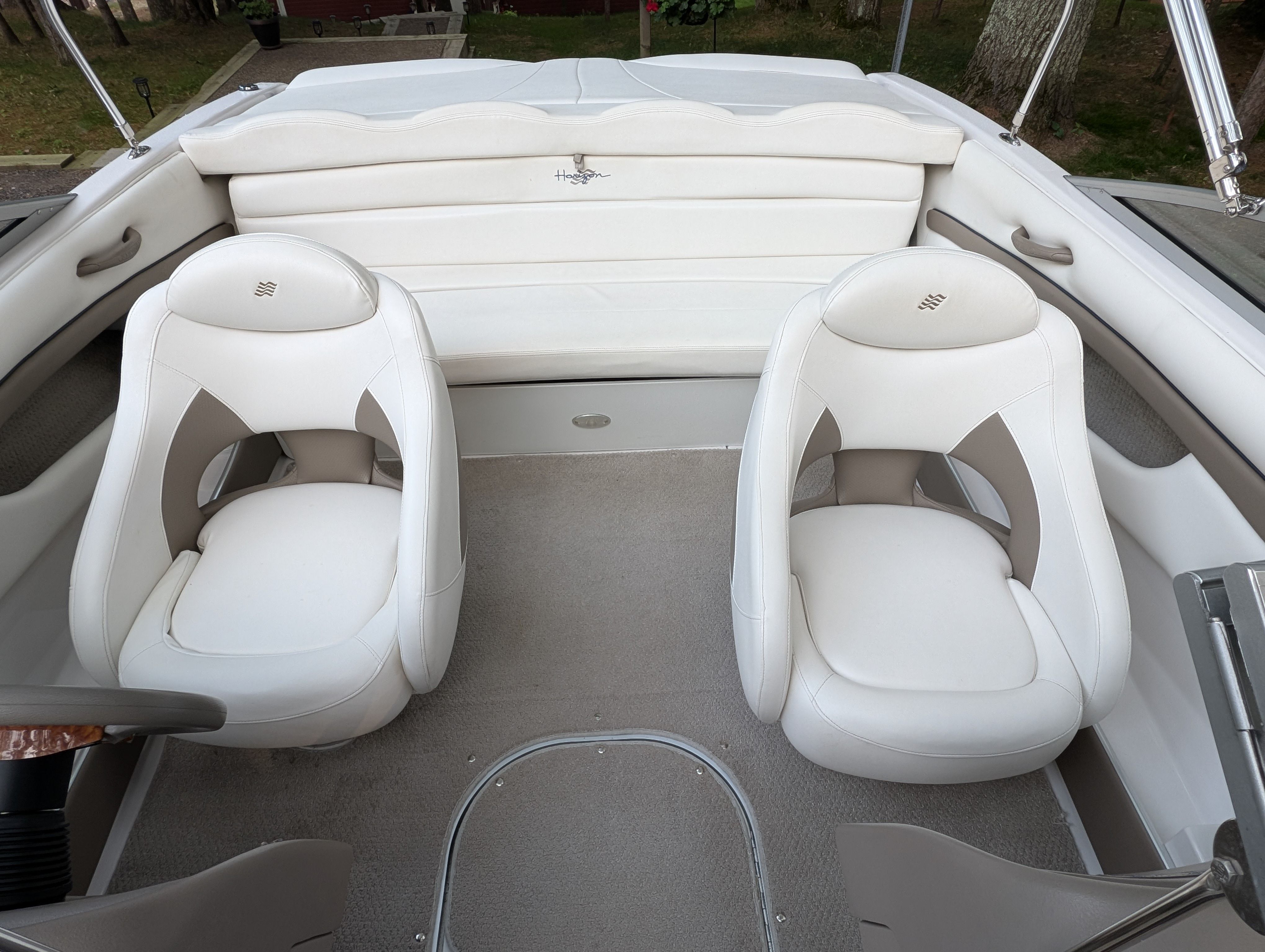 Interior of a 2004 Four Winns 190 Horizon with two white bucket seats and a padded rear bench.