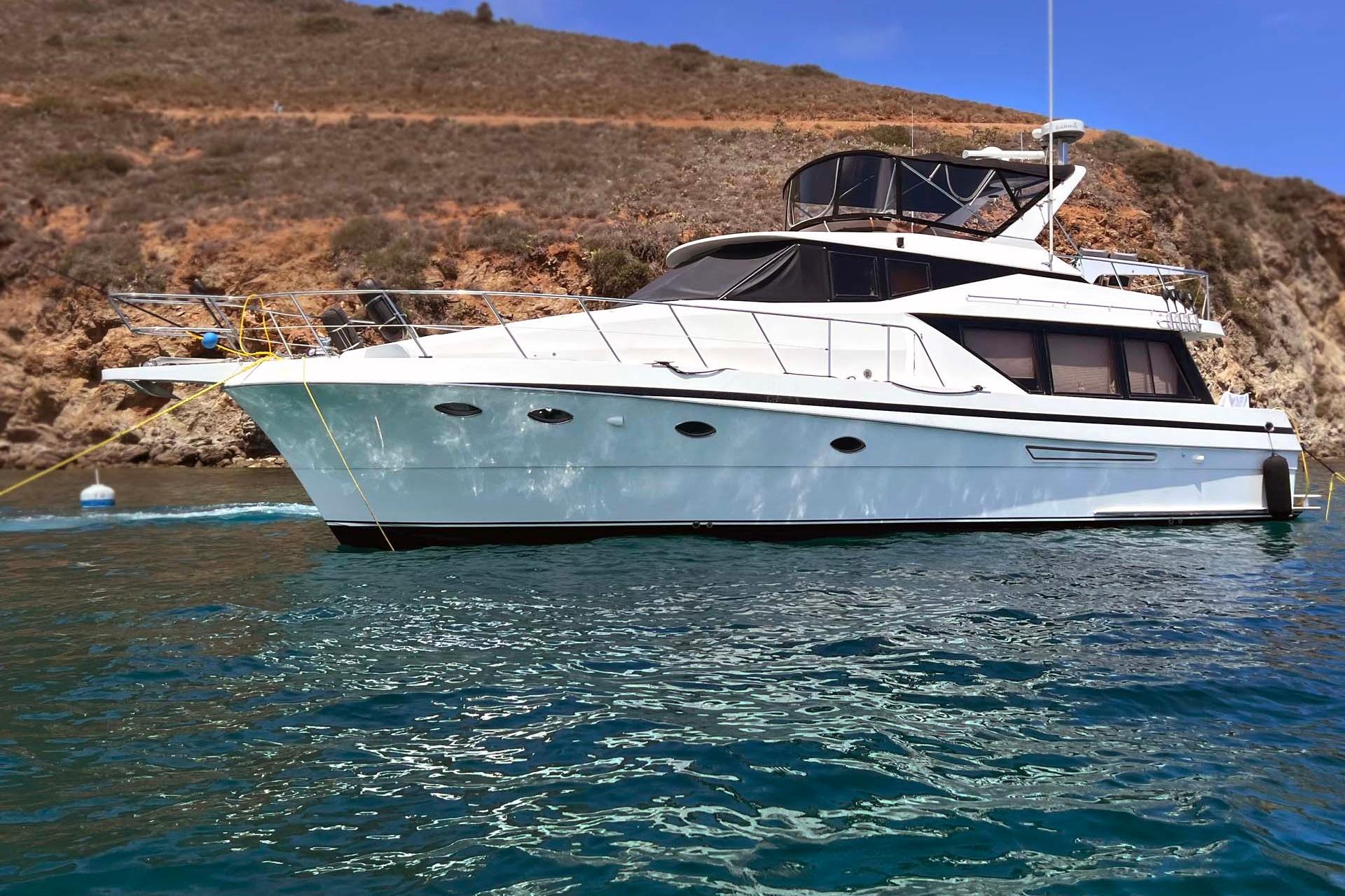 1997 McKinna 48' Pilot House yacht anchored near rocky coastline.