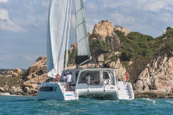 2025 Seawind 1170 catamaran sailing near rocky coastline.