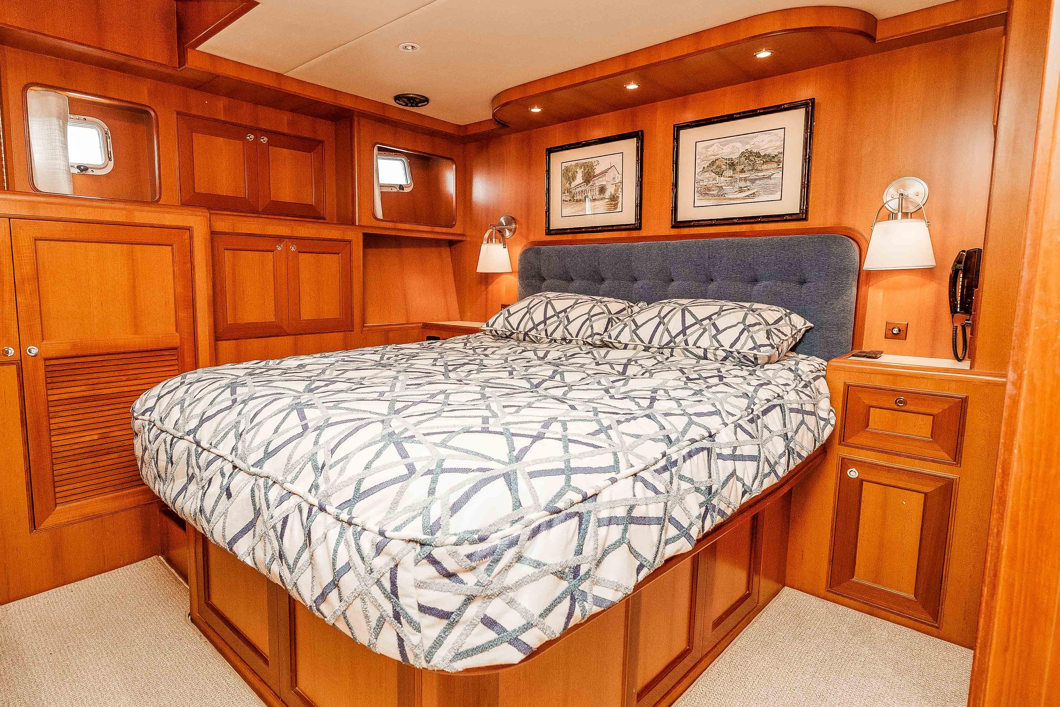 Luxurious 2005 Offshore Yachts 54 Pilothouse bedroom with elegant wood paneling and cozy bedding.