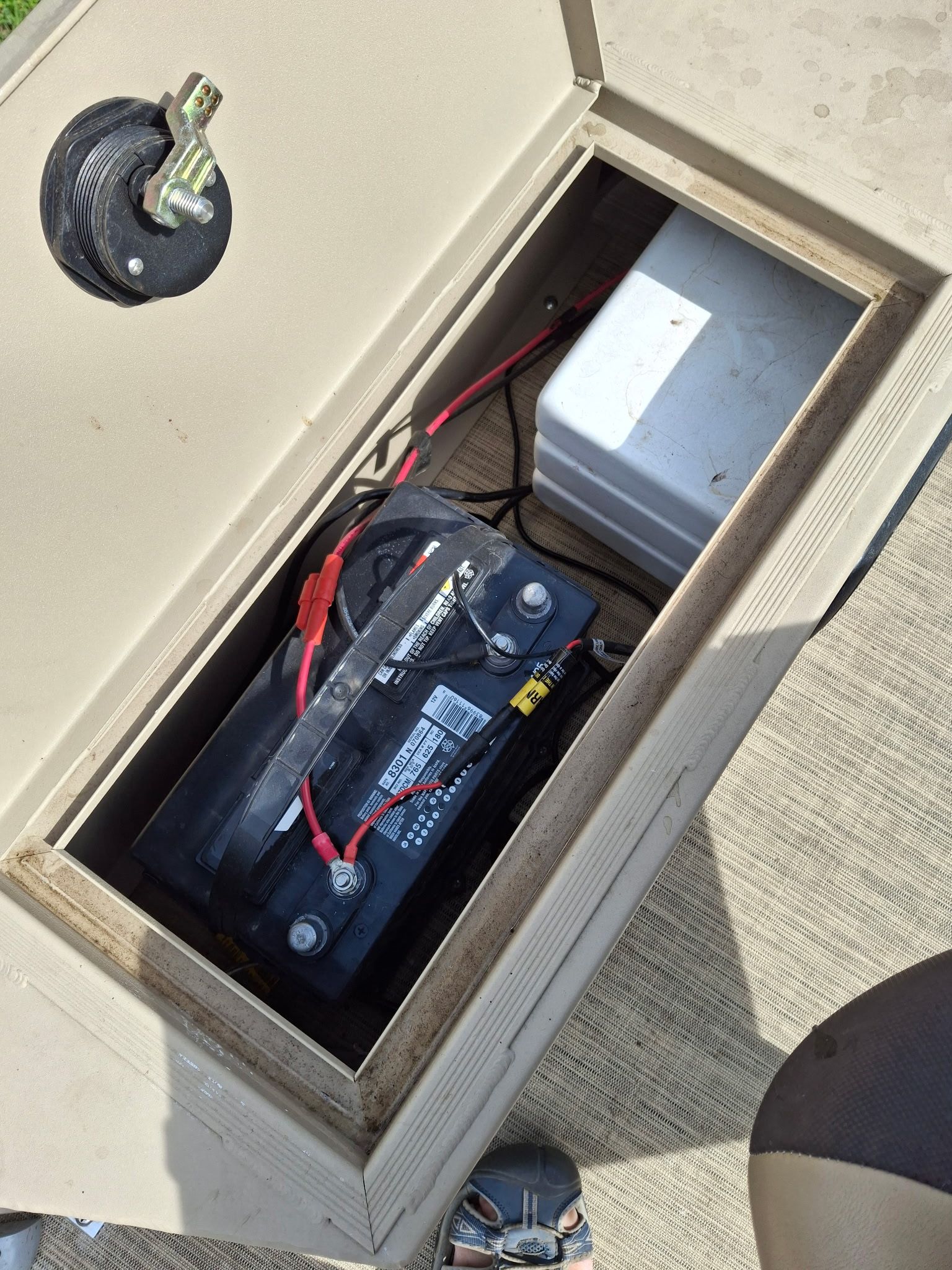 A battery compartment on a boat with a black battery and cables.