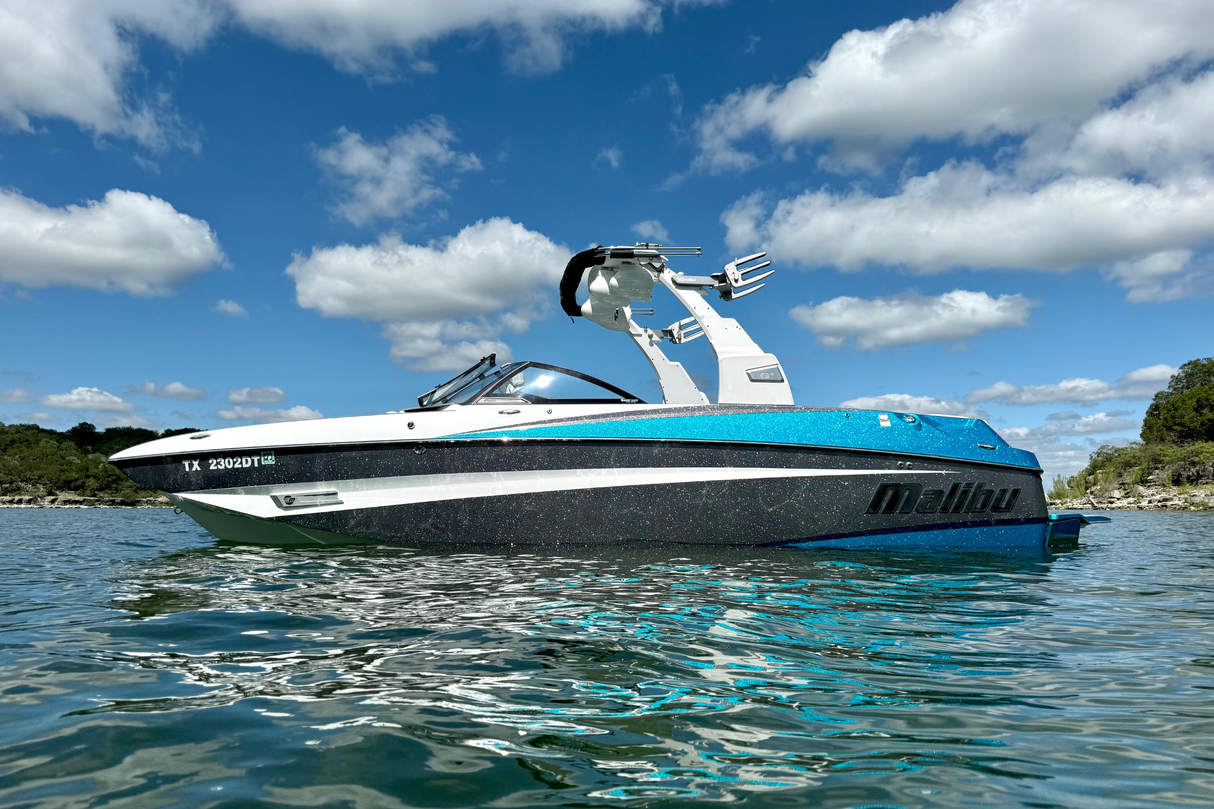 2017 Malibu M235 boat on water under blue sky with clouds.