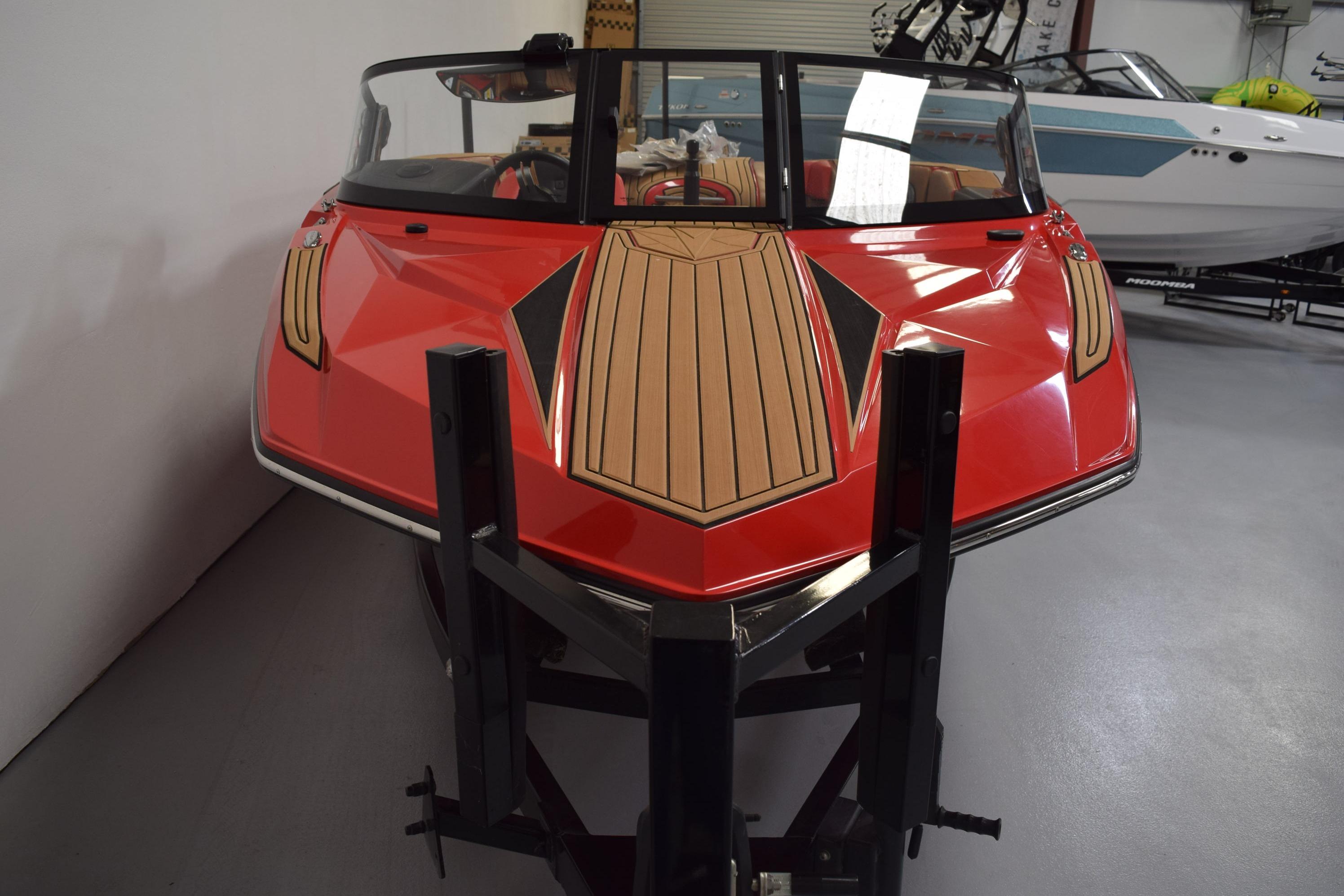 2024 Nautique Ski Nautique boat with red hull and wood accents in showroom.