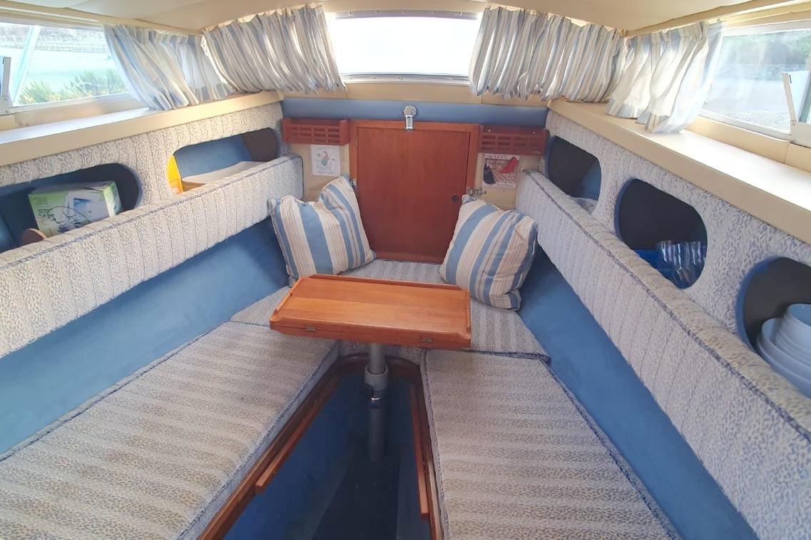Interior of 1989 Fairey Spearfish MKIII boat with cozy seating and wooden table.