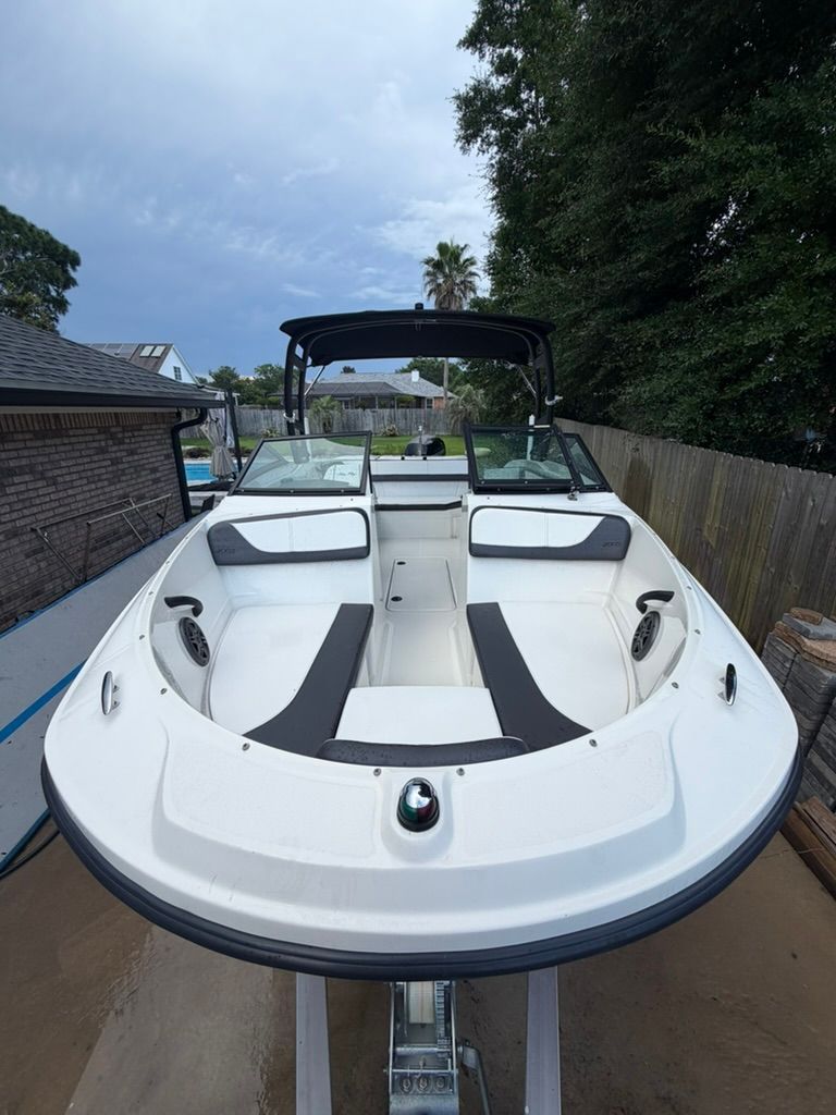 A Sea Ray SPX 210 Outboard boat on a trailer in a backyard setting.