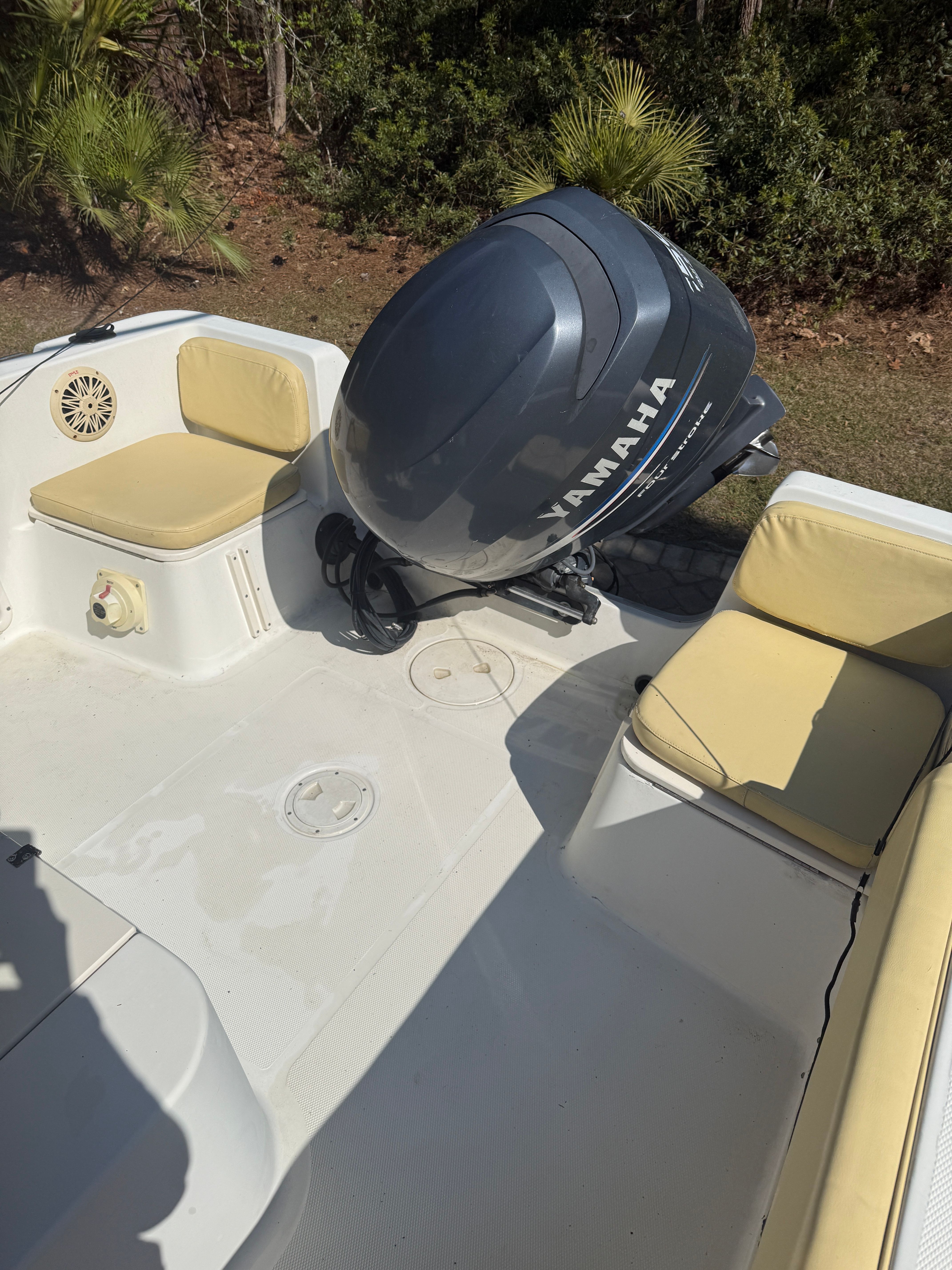 A boat with a Yamaha outboard motor and beige seat cushions, surrounded by trees.