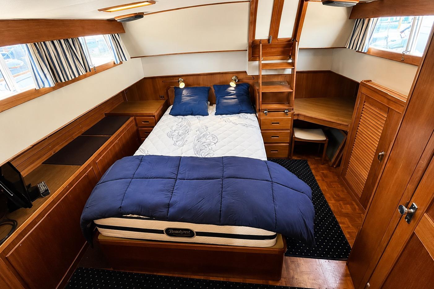 Luxurious 1989 Grand Banks 42 Classic yacht bedroom with wood furnishings and cozy bedding.