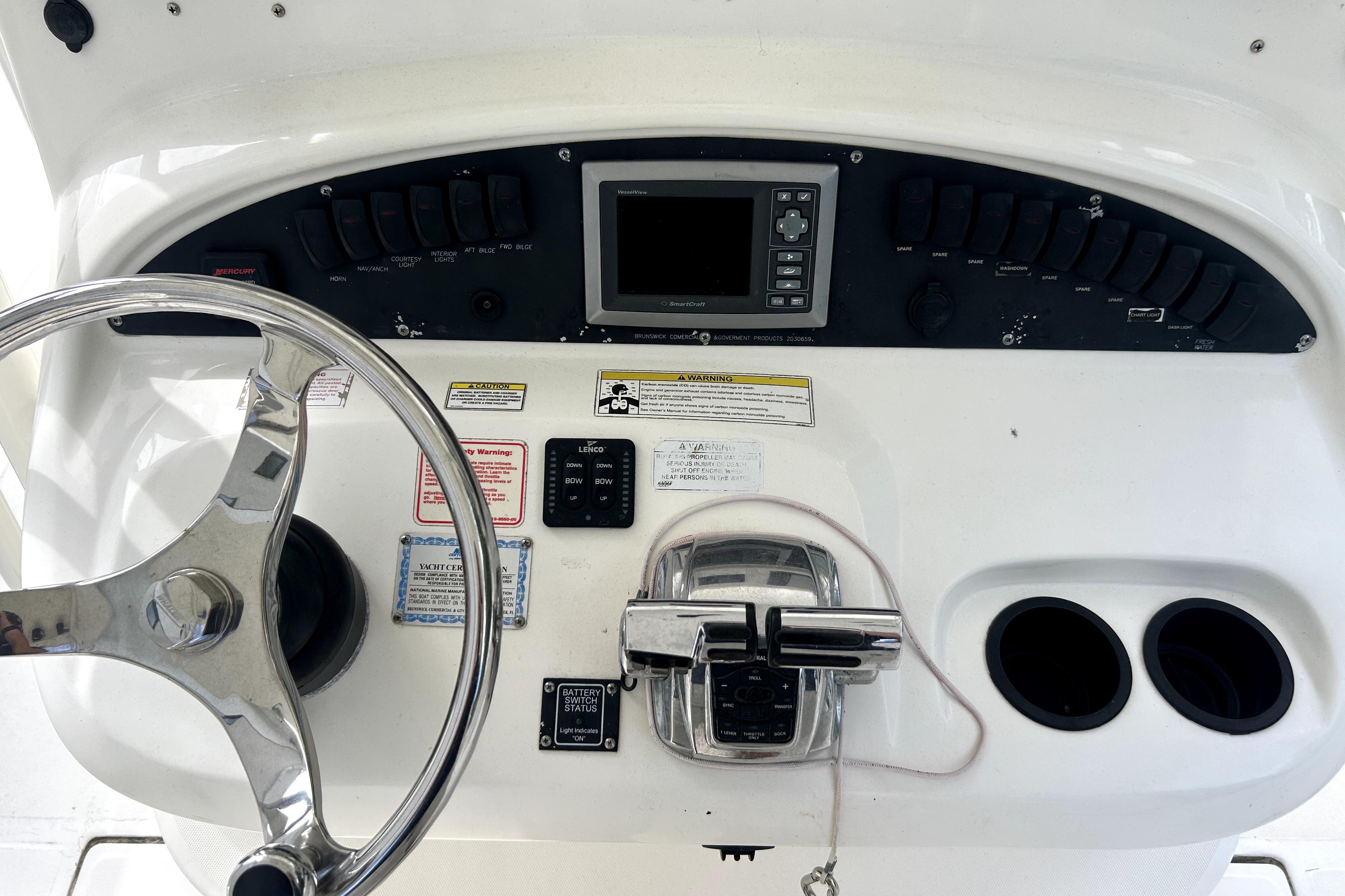 Control panel of a 2012 Boston Whaler 320 Outrage boat with steering wheel and switches.