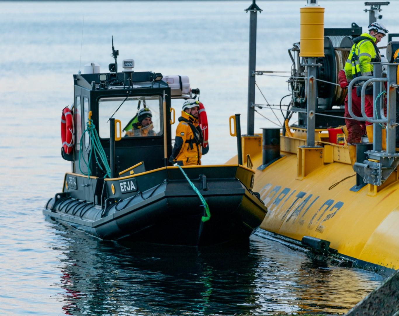 Small Arran 7m boat docking beside a larger vessel, crew members in safety gear, 2025.