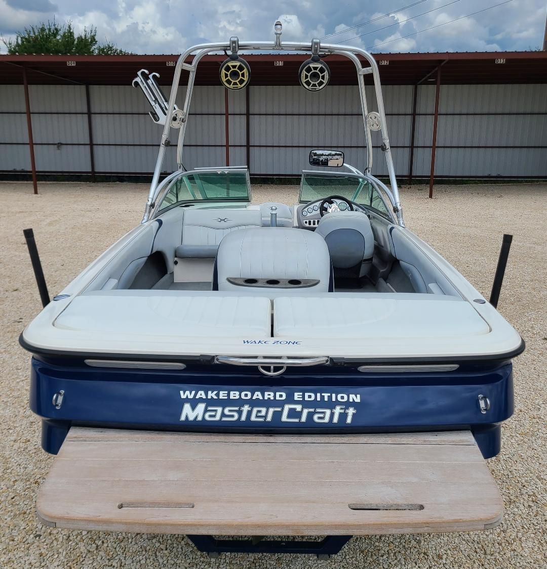 2003 MasterCraft X-9 Wakeboard Edition boat with tower and speakers, parked outdoors.