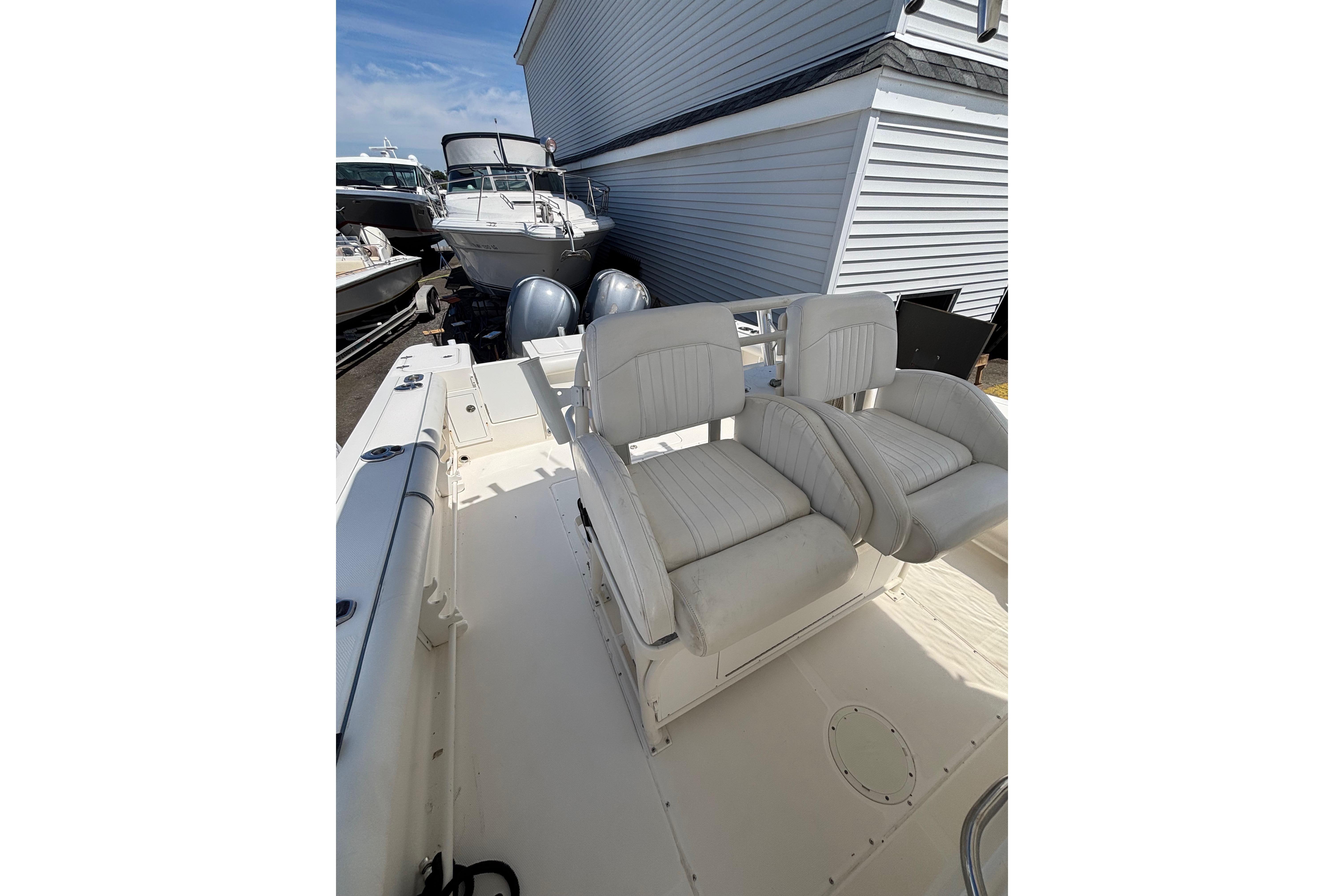 2006 Edgewater 318CC boat interior with dual white cushioned seats, docked near other boats.