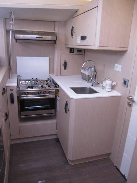 Modern kitchen in 2024 Jeanneau 60 yacht with stove, sink, and cabinetry.