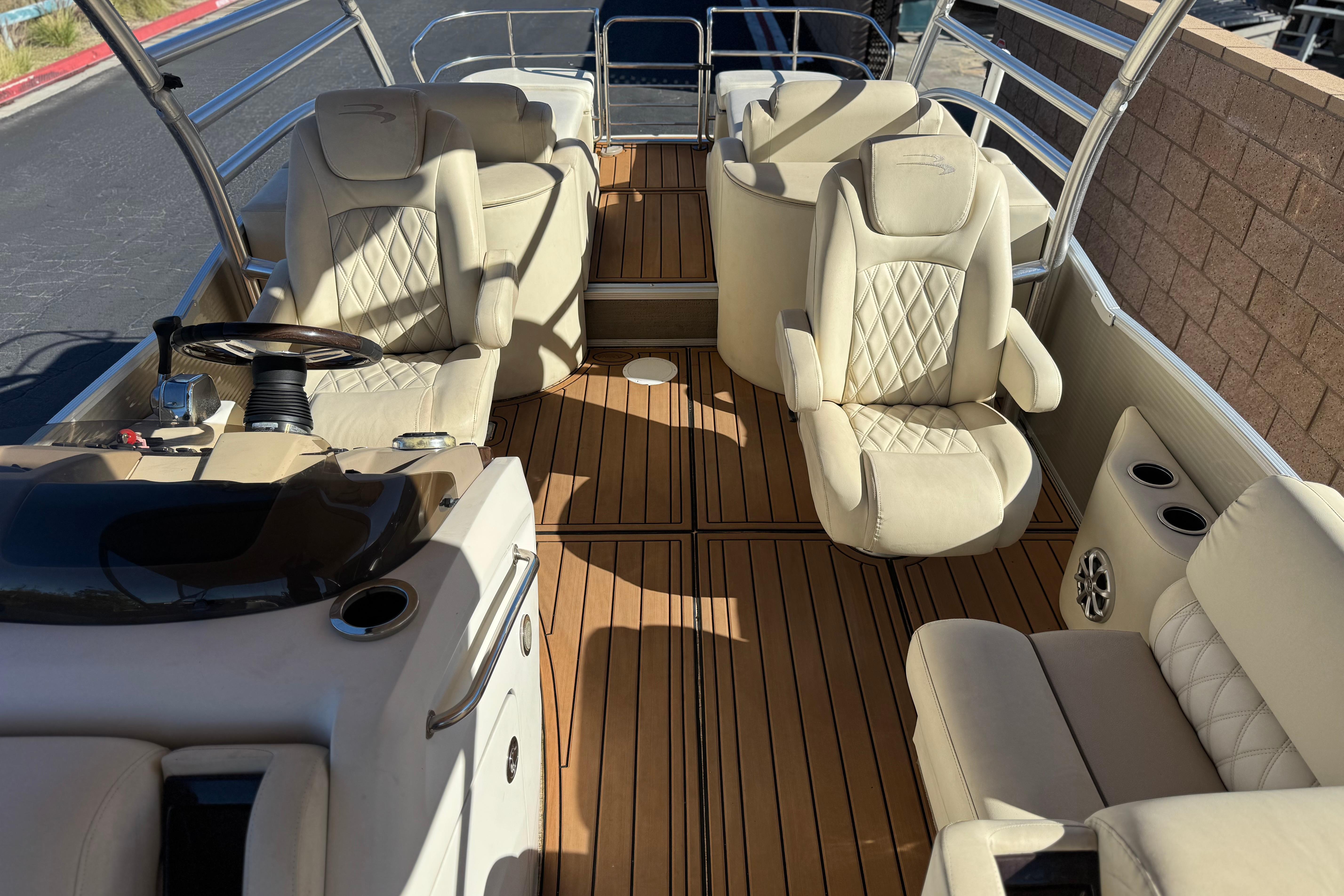 2013 Bennington 2575QCW I/O boat interior with beige seating and wooden flooring.
