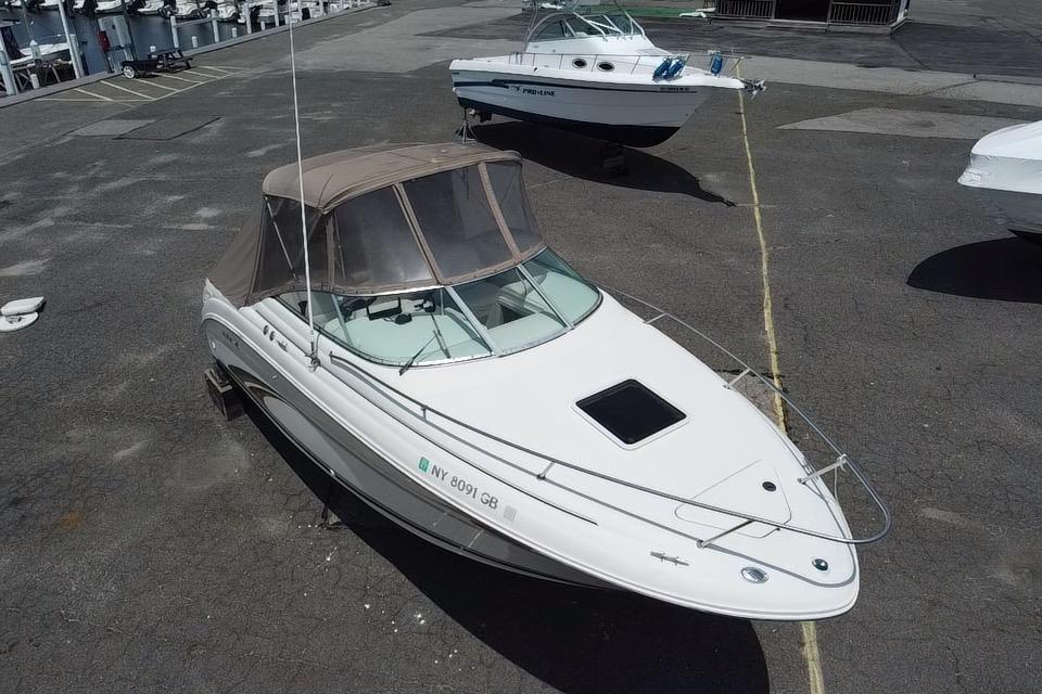 2001 Sea Ray 245 Weekender boat with canopy, parked on asphalt lot.