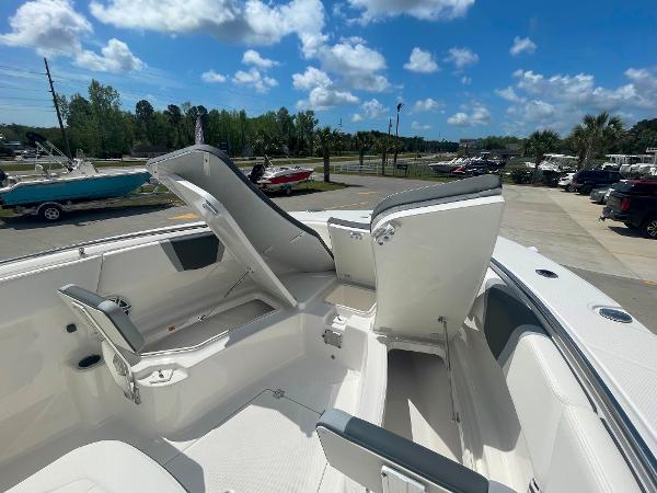 2023 Robalo R270 boat with open storage compartments on a sunny day.