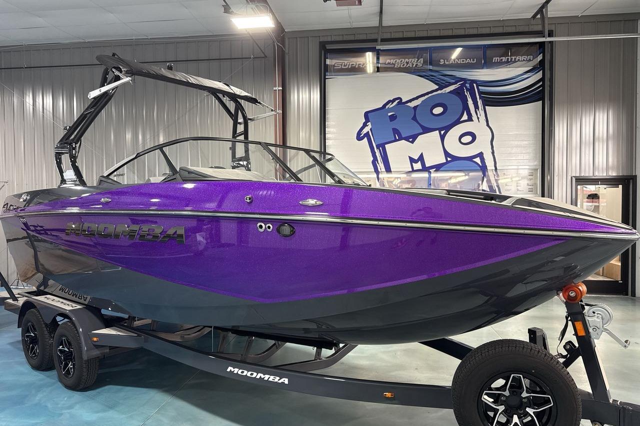 A purple 2026 Moomba Craz boat is on a trailer inside a warehouse.