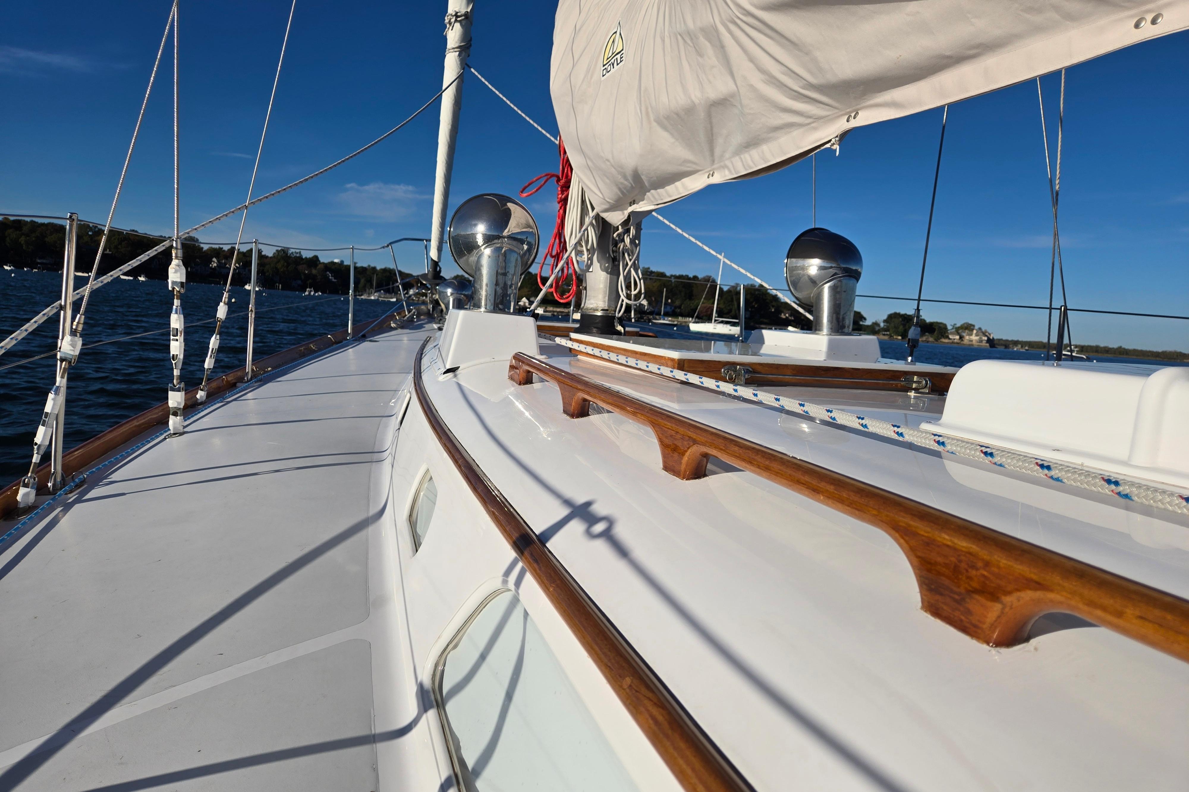 1970 Hinckley Bermuda 40 sailboat deck with wooden accents and rigging, sailing on a sunny day.