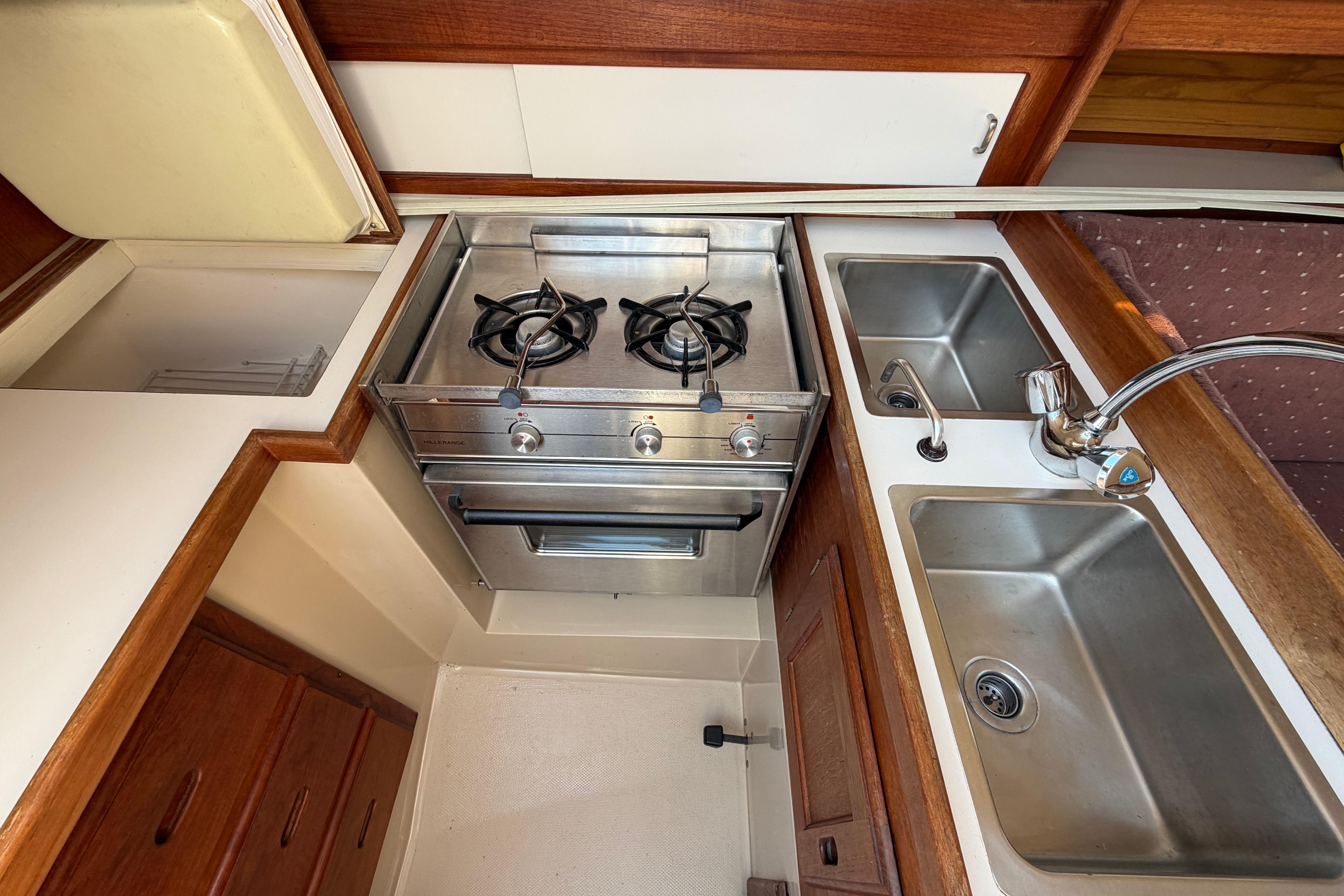 Compact kitchen in a 1988 Catalina 30 MkII sailboat with stove and dual sinks.