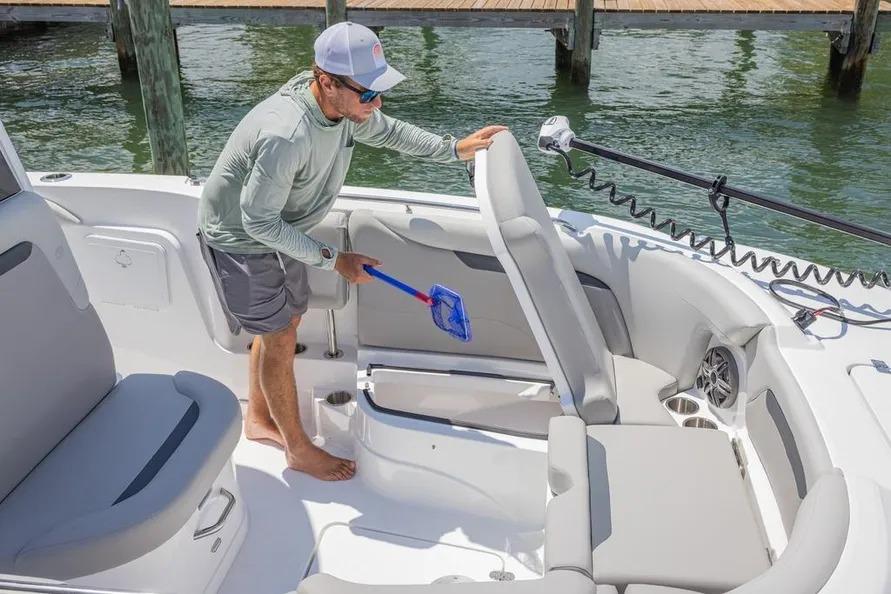 Man cleaning 2025 Hurricane Center Console 24 OB boat interior with a net.
