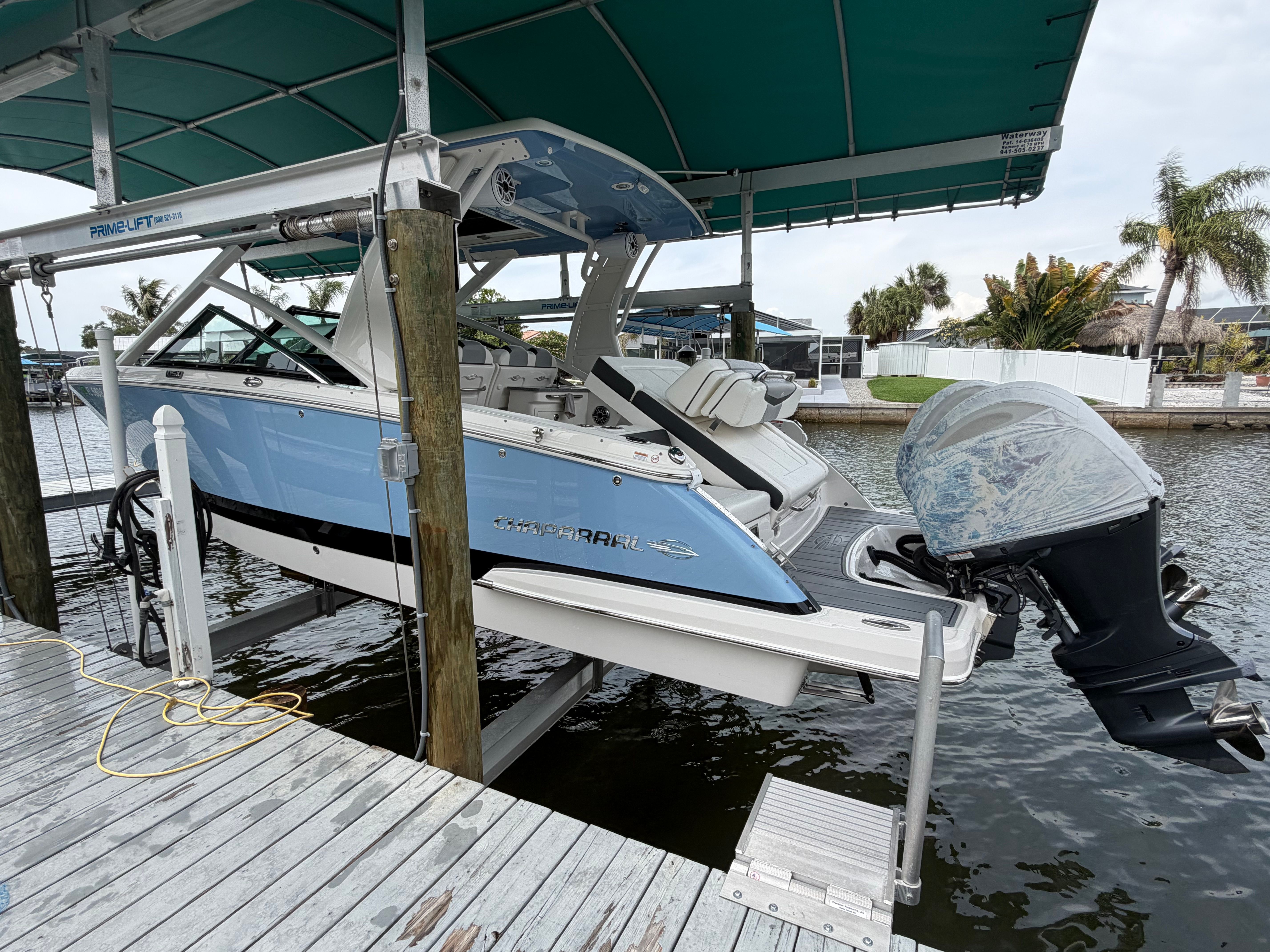 A Chaparral 280 OSX boat is lifted in a covered dock, featuring an outboard motor.