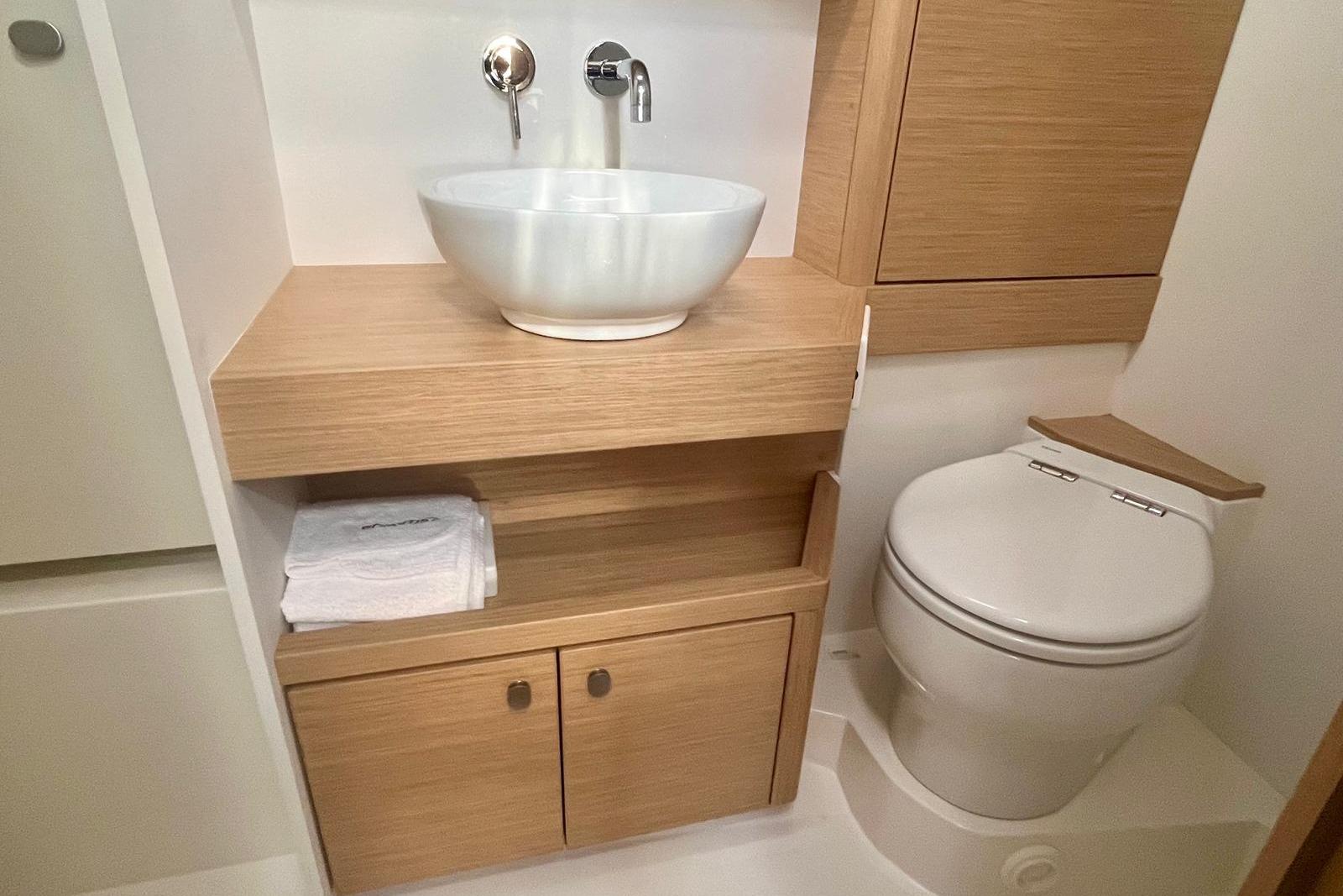Modern bathroom in 2023 Grand Soleil 42 LC yacht with wooden cabinetry and vessel sink.