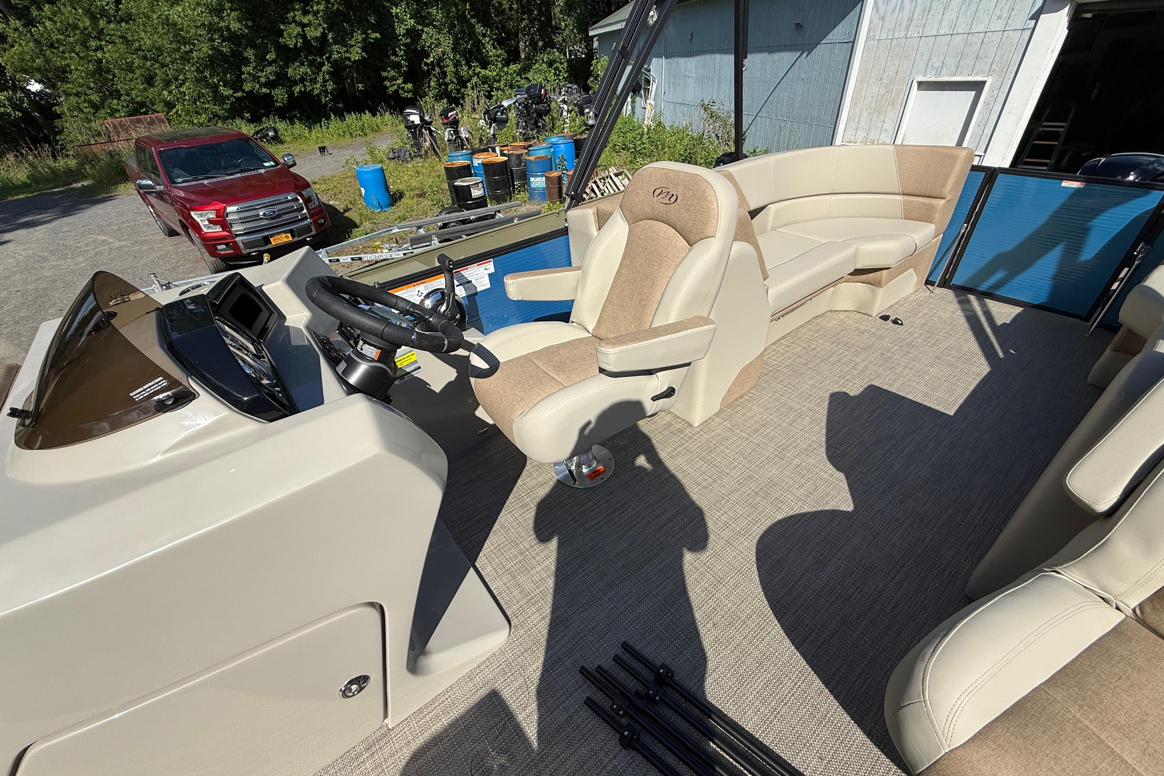 2027 Manitou Aurora RF 23 pontoon boat interior with beige seating and steering console.