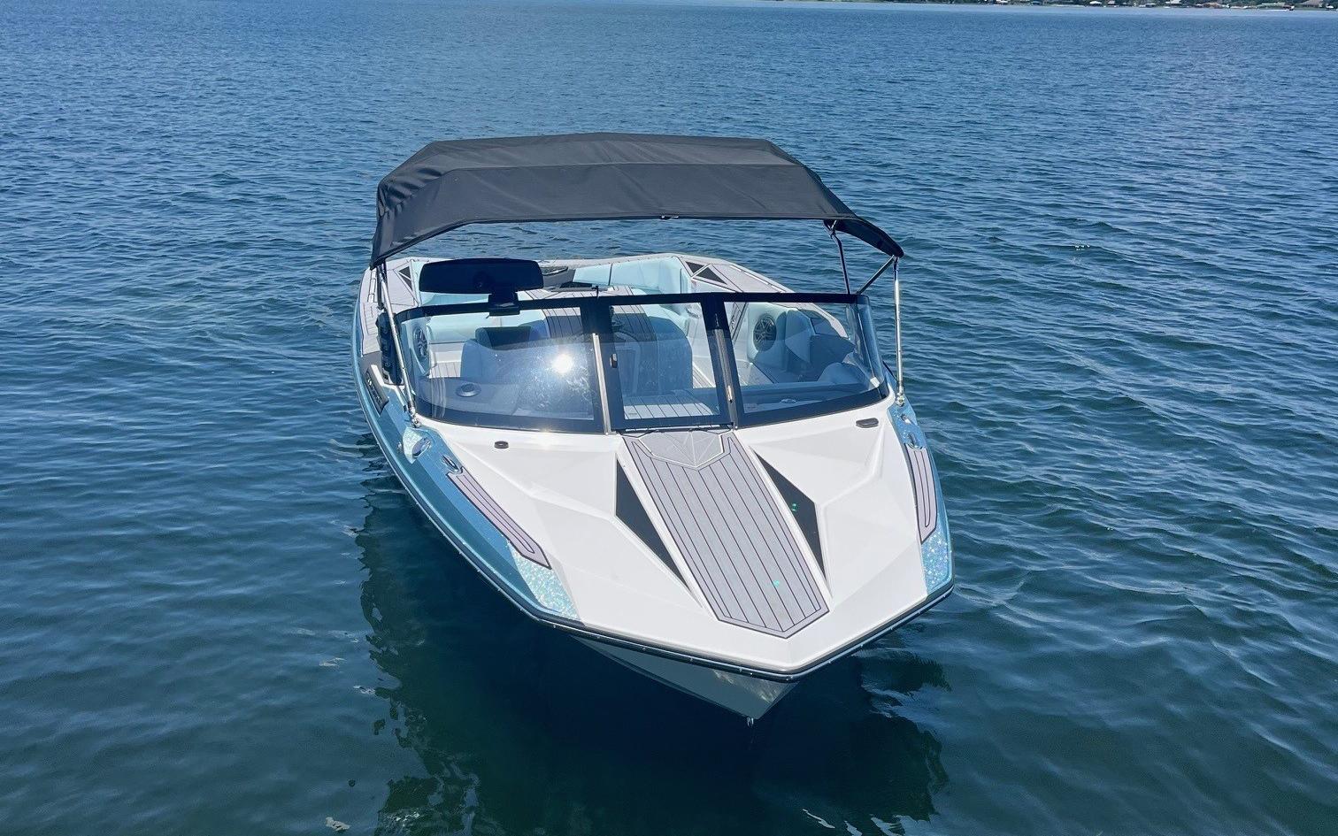 2025 Nautique Ski boat on calm water, featuring sleek design and canopy.