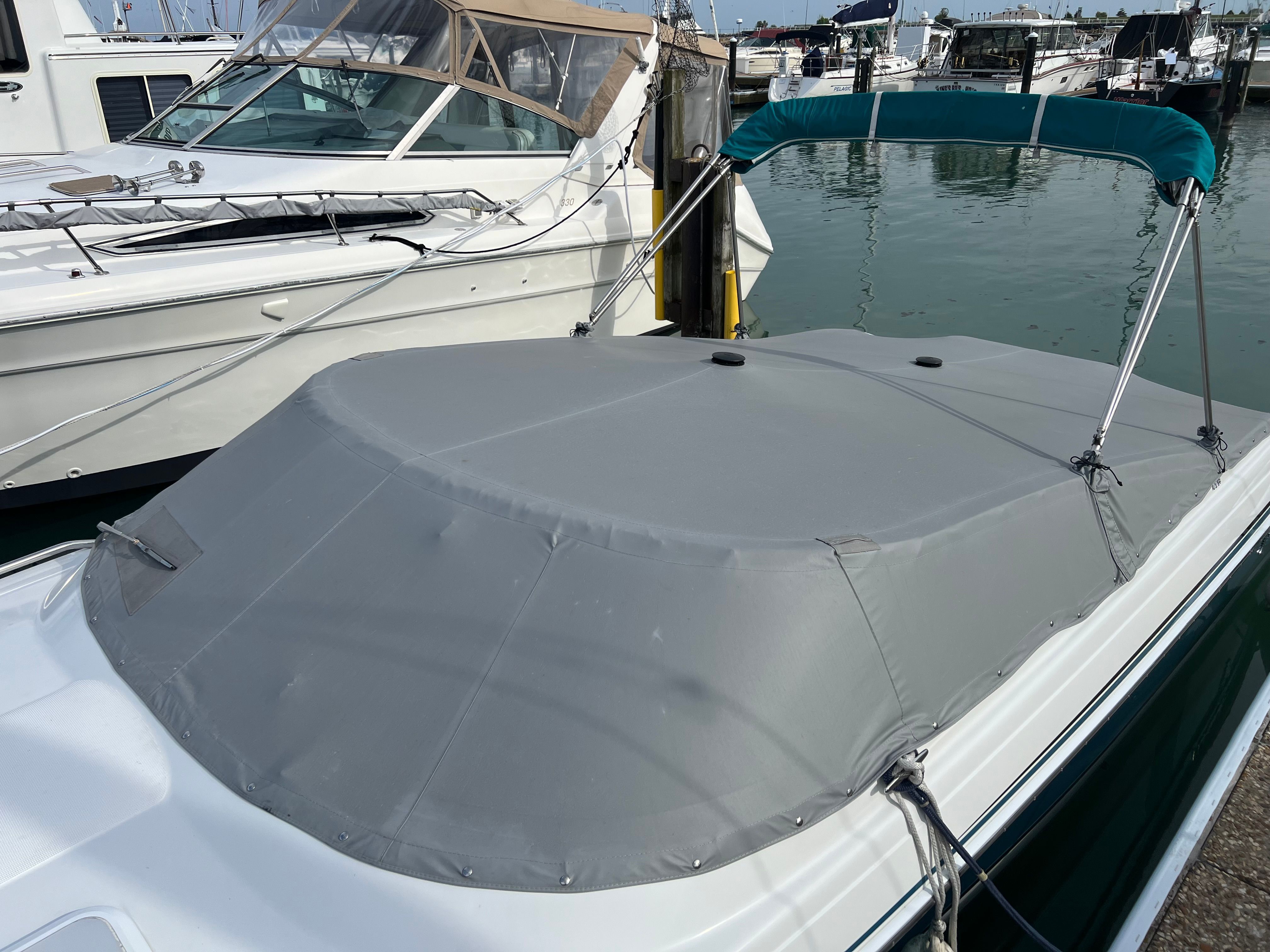 A 2005 Formula 260 Sun Sport with a gray cover, docked in a marina next to other boats.