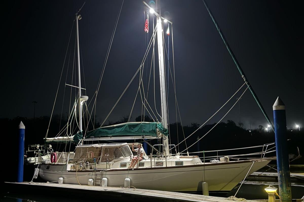 1978 Herreshoff 50 sailboat docked at night, illuminated by lights.