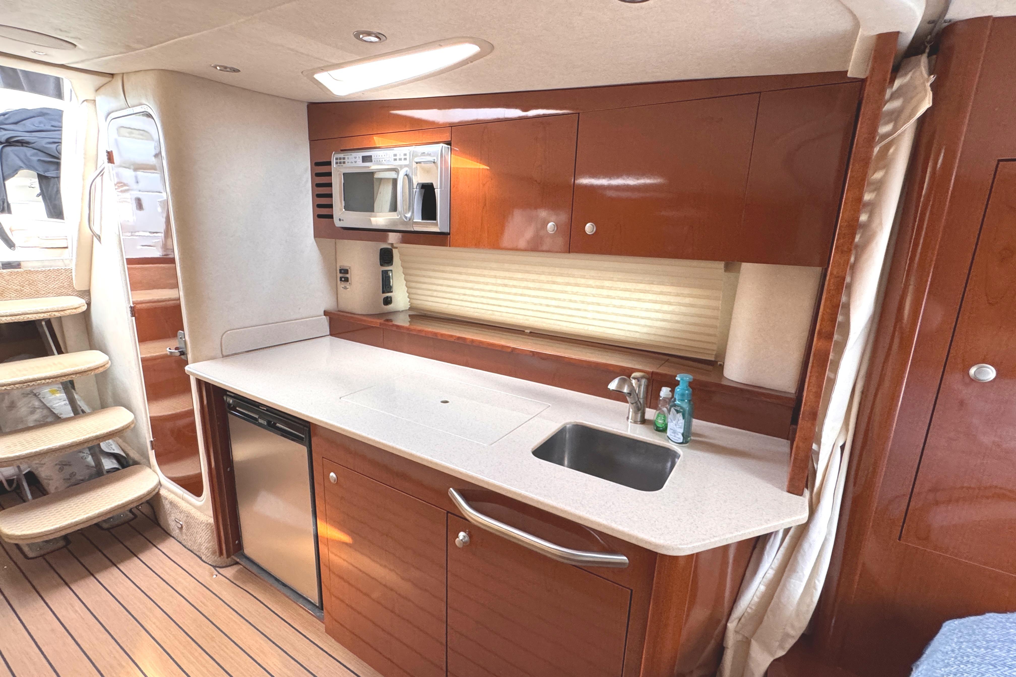 Luxurious 2008 Sea Ray Sundancer 350 yacht interior with modern kitchenette and wooden cabinetry.
