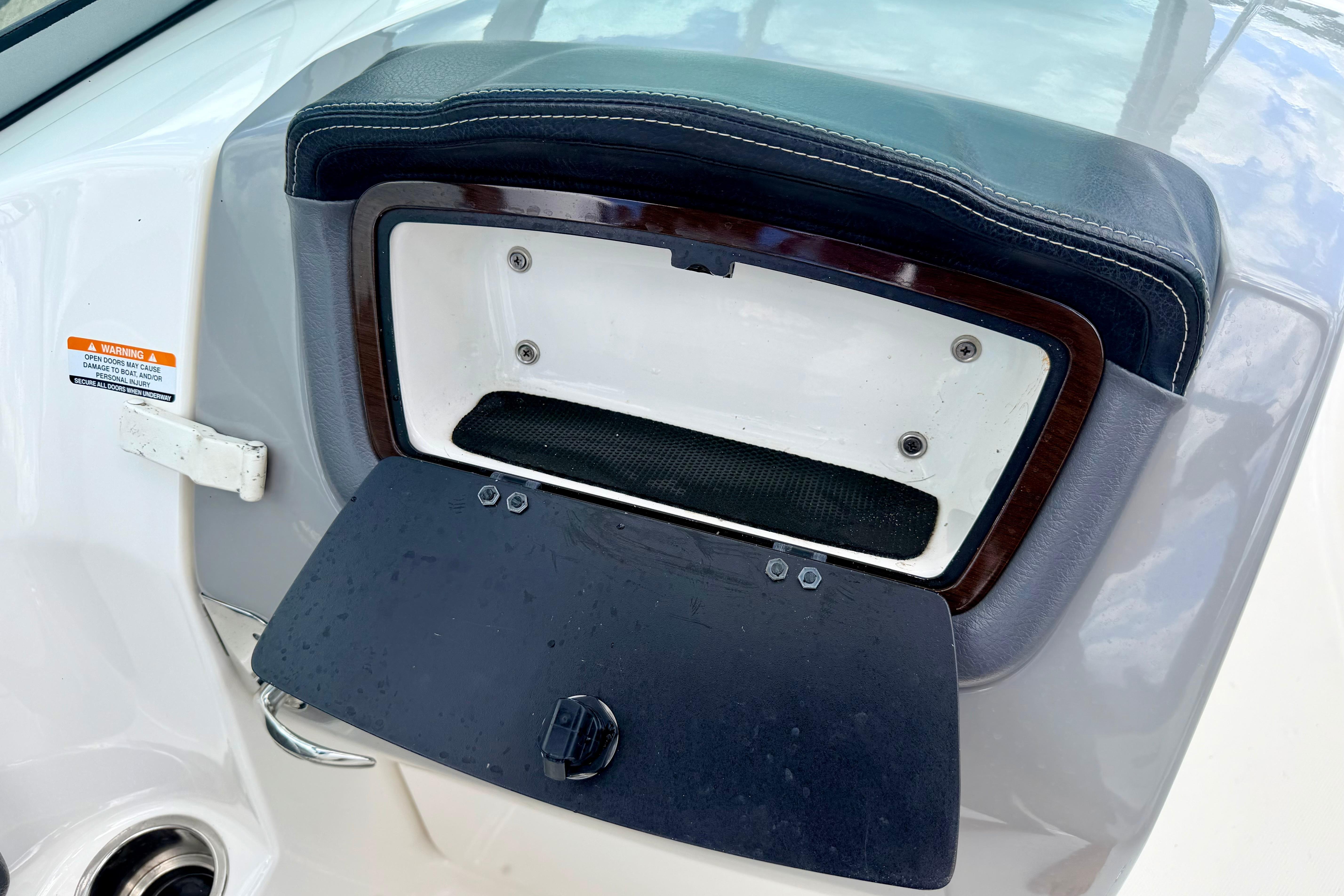 2015 Chaparral Sunesta 264 boat storage compartment with open lid and warning label.