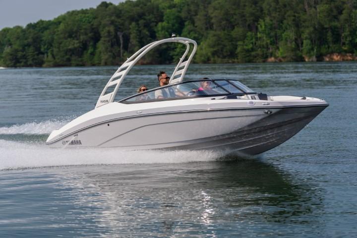 2026 Yamaha Boats 195S cruising on a lake with lush green forest backdrop.