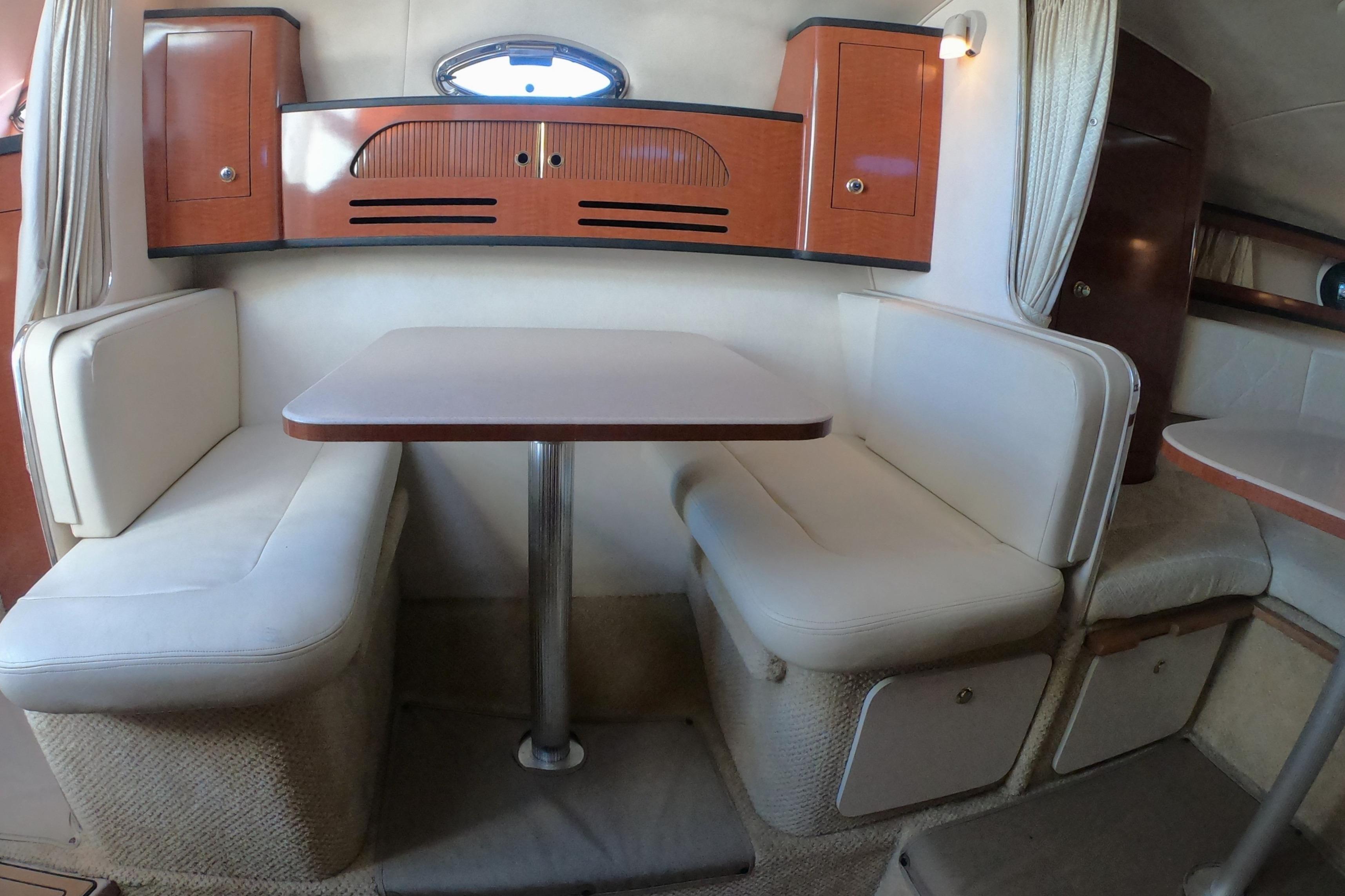 2004 Sea Ray Sundancer 280 interior with cozy dining area and wooden cabinetry.