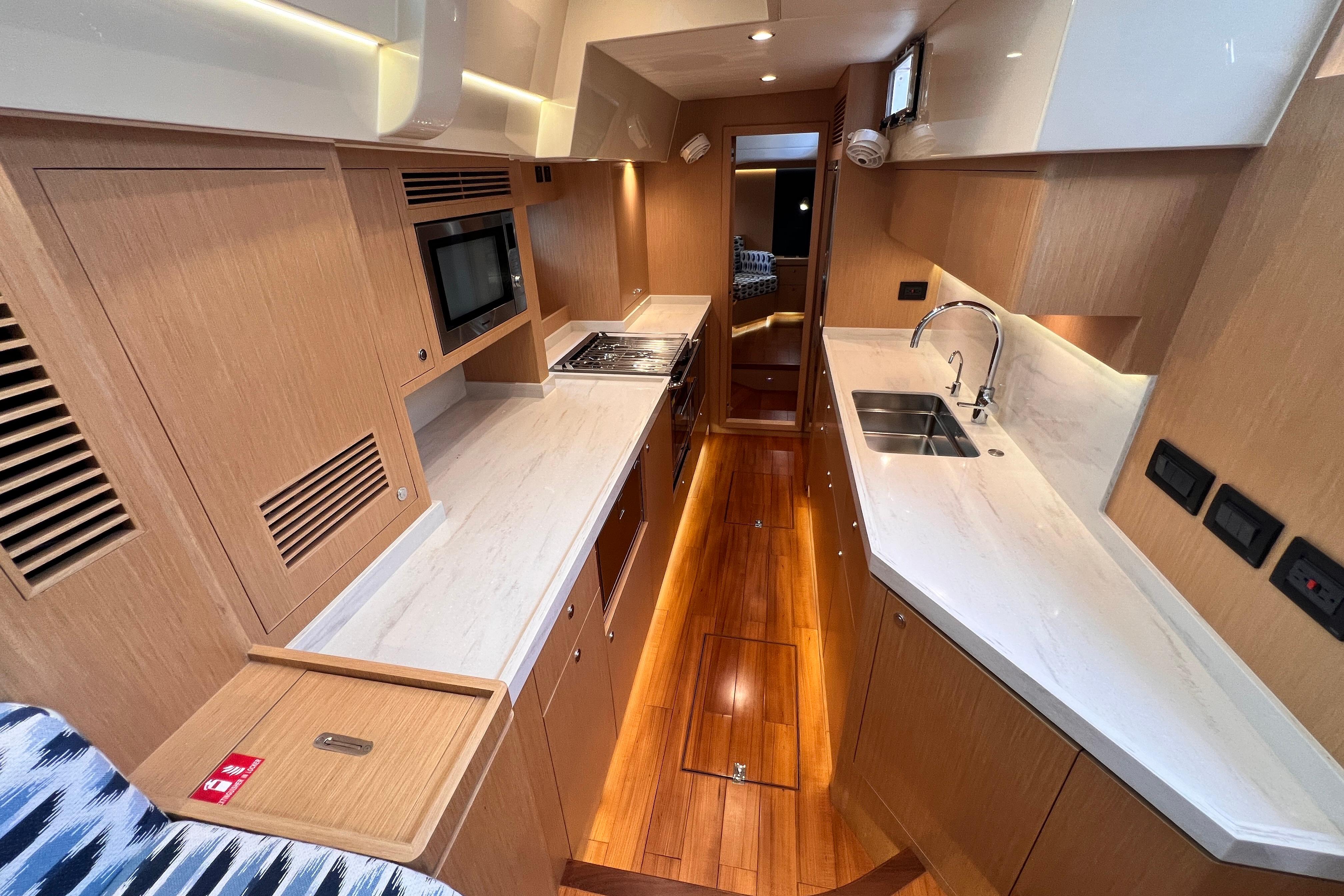 Luxurious interior of 2024 Hylas H57 yacht featuring modern kitchen design and wooden flooring.
