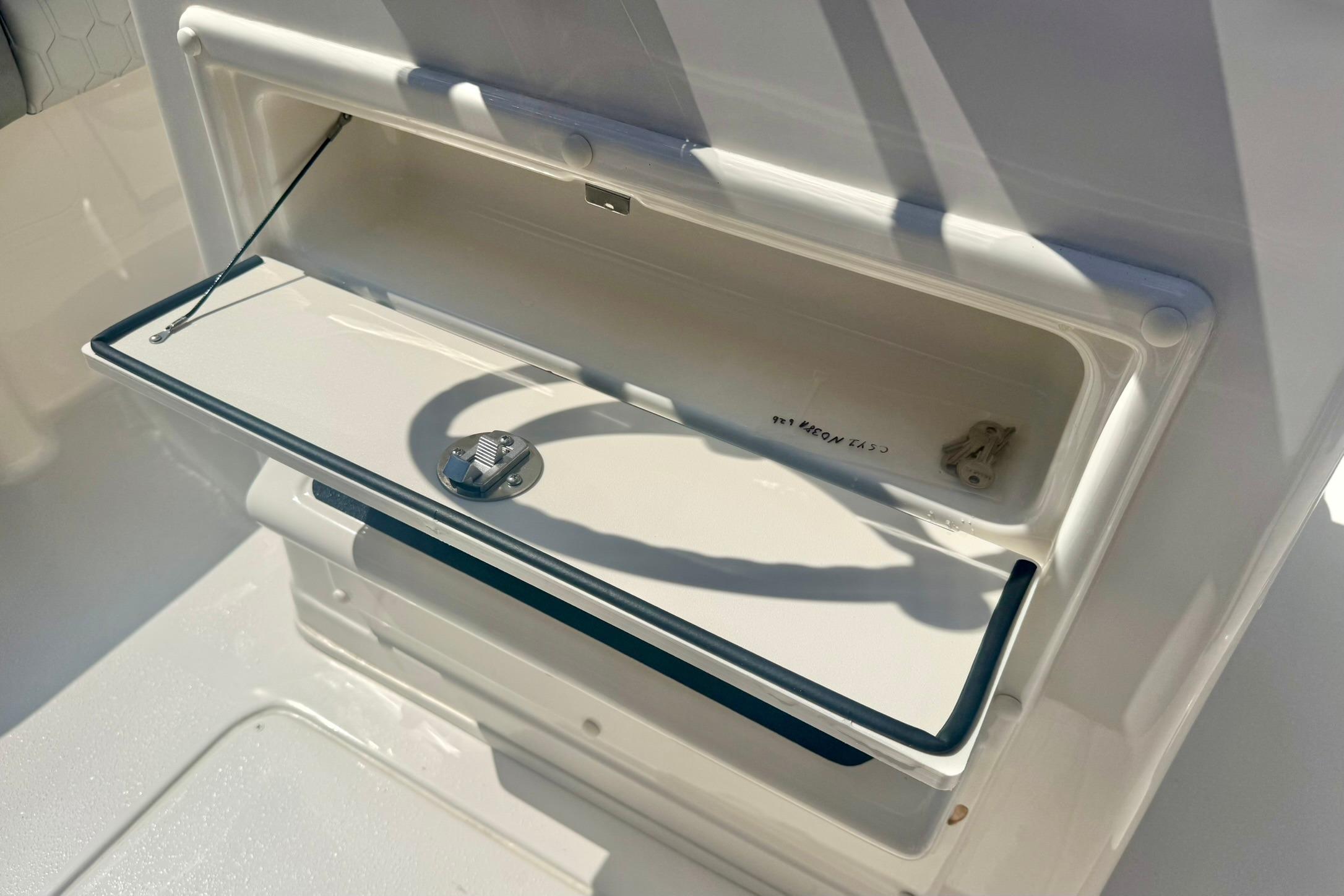 Storage compartment on a 2026 Carolina Skiff 21 Ultra Elite boat, open and sunlit.