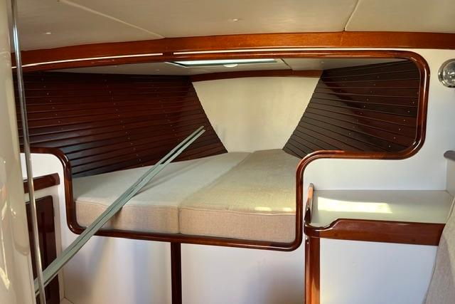 Interior cabin of a 2006 Morris 36 sailboat with wooden accents and cozy bedding.